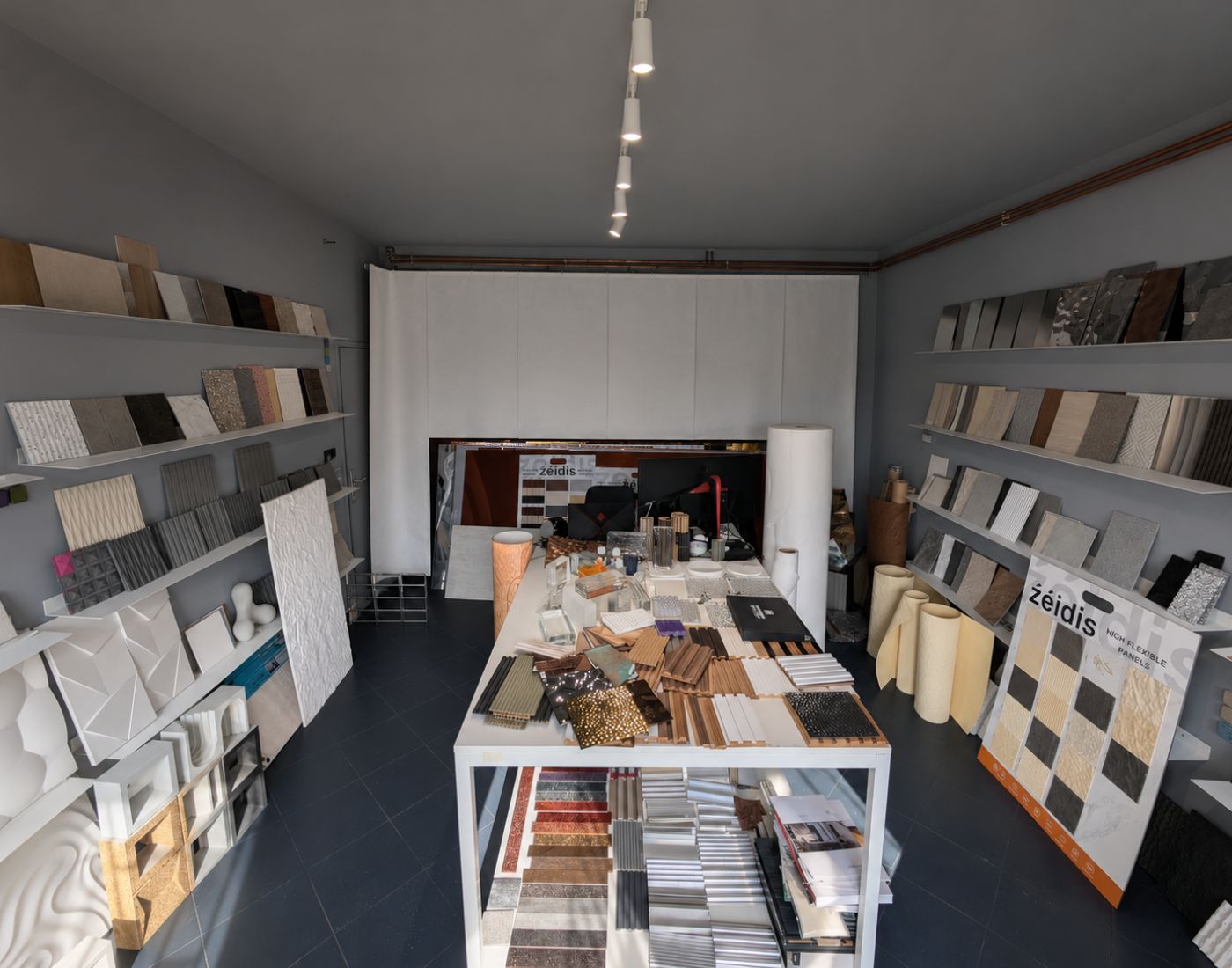 Showroom with shelves and tables displaying various decorative wall panels and textured tiles in different colors.