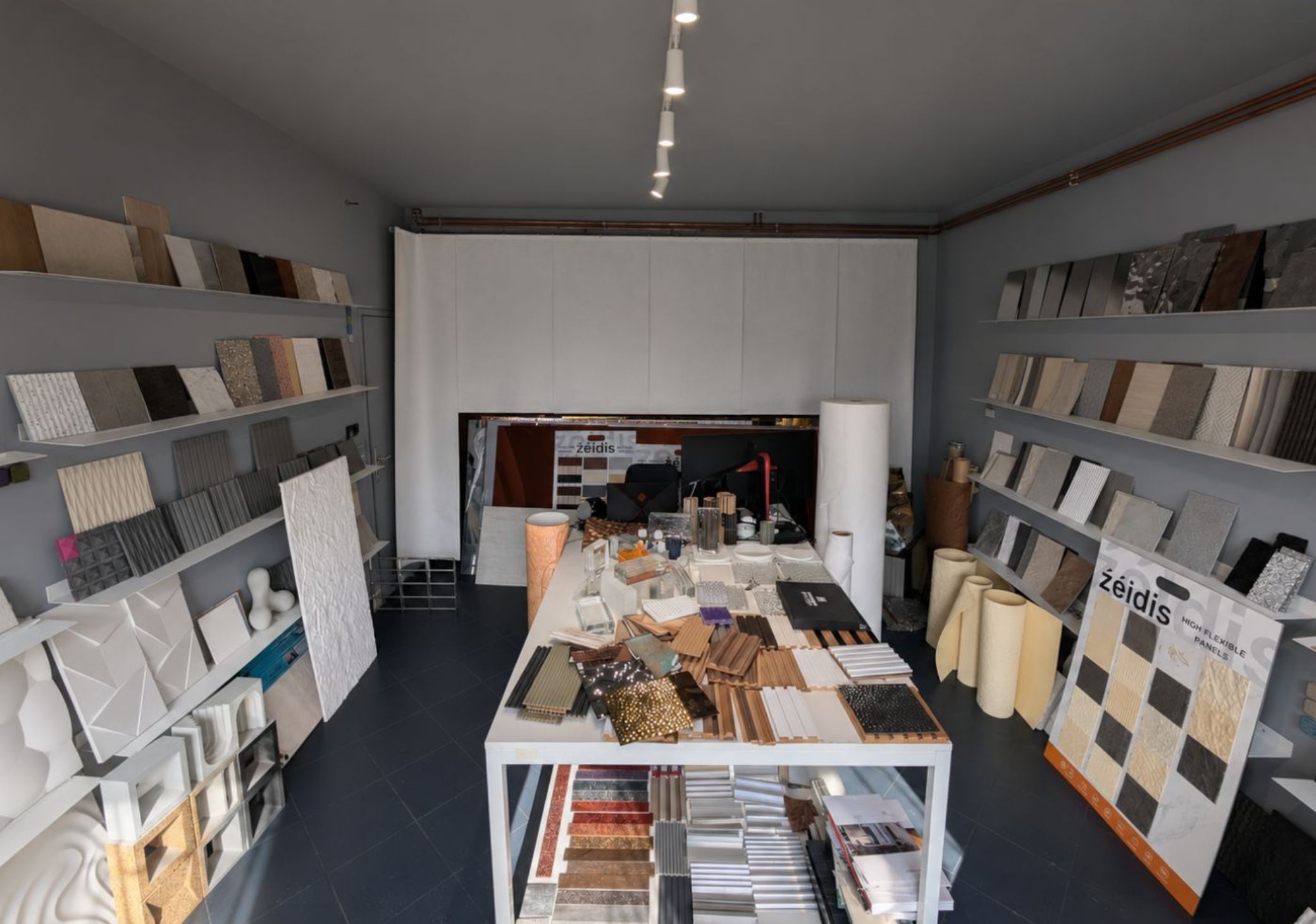 Showroom with various decorative wall panel samples displayed on shelves and a central table.