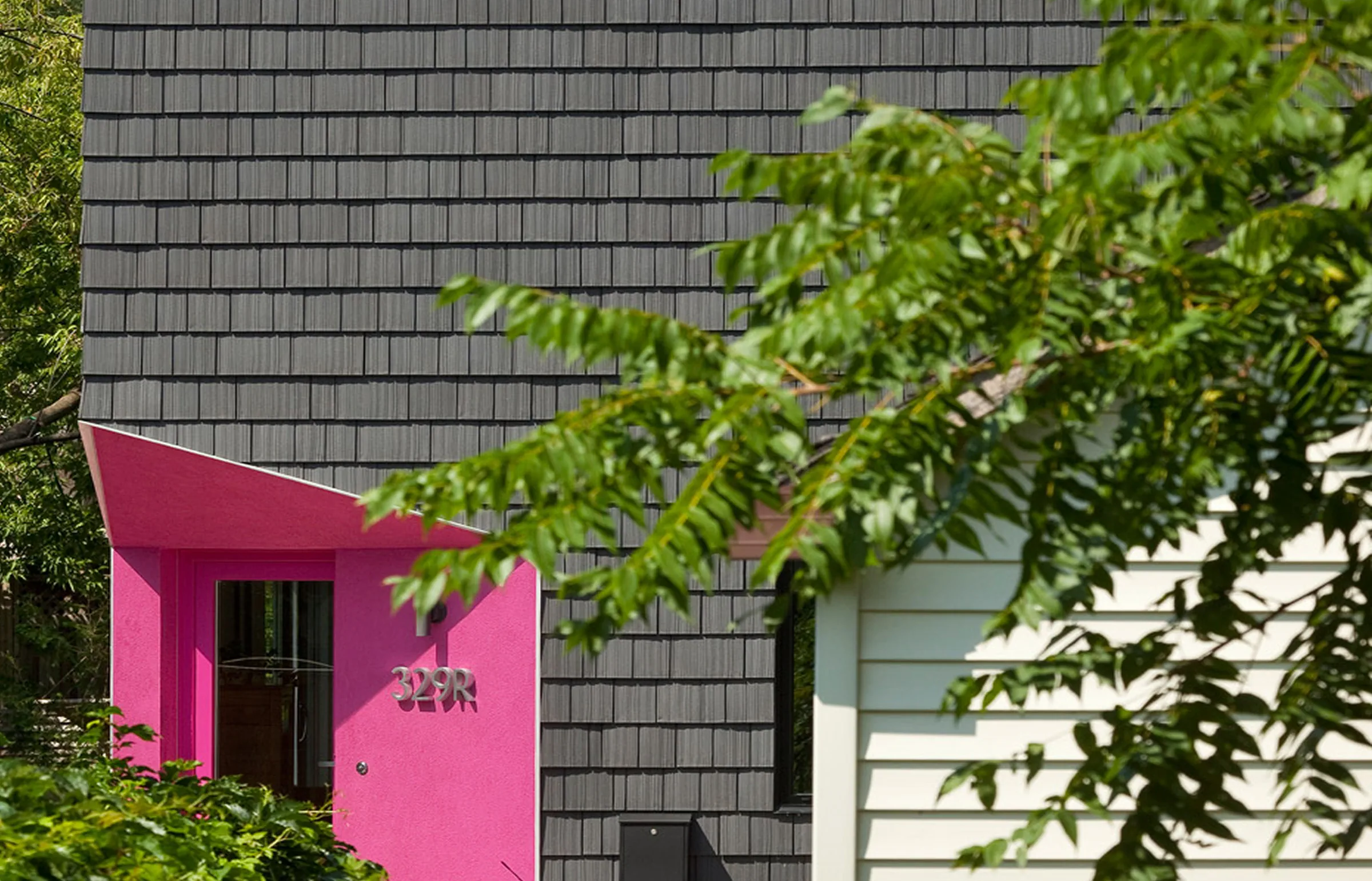 Dark grey shake-style wall cladding above a bright pink recessed entrance.