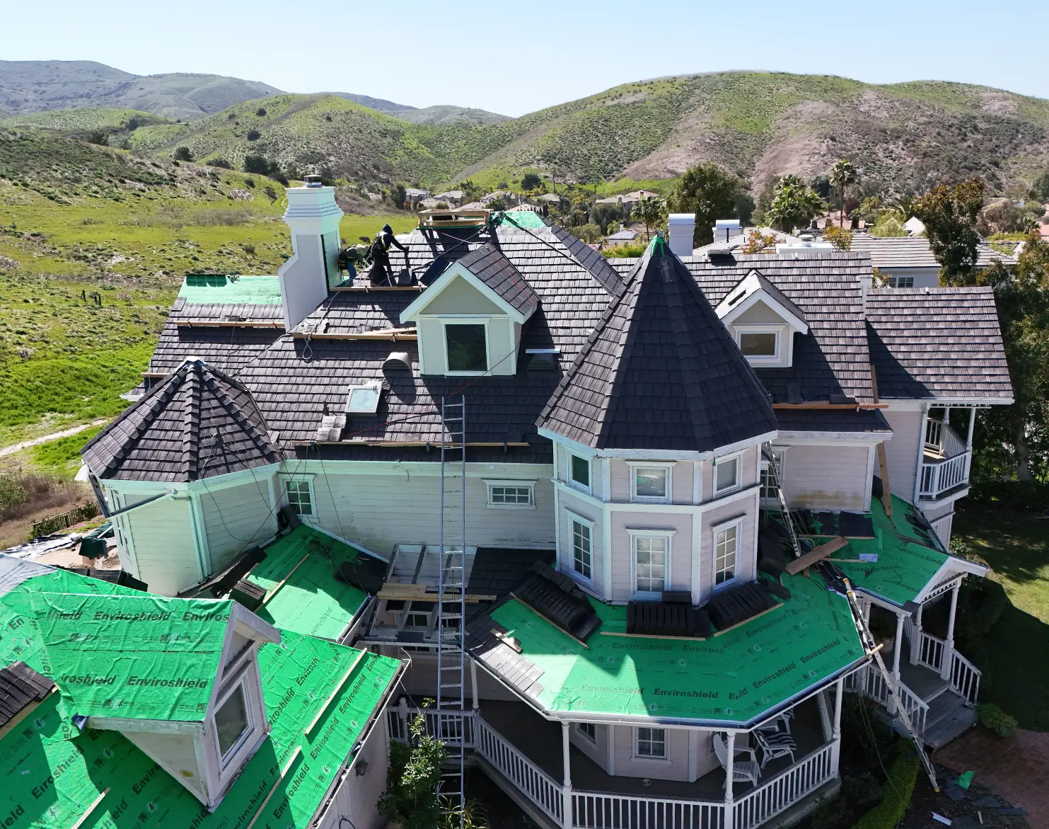 Contractors installing an aged cedar Enviroshake synthetic shake roof with Enviroshield synthetic underlayment visible