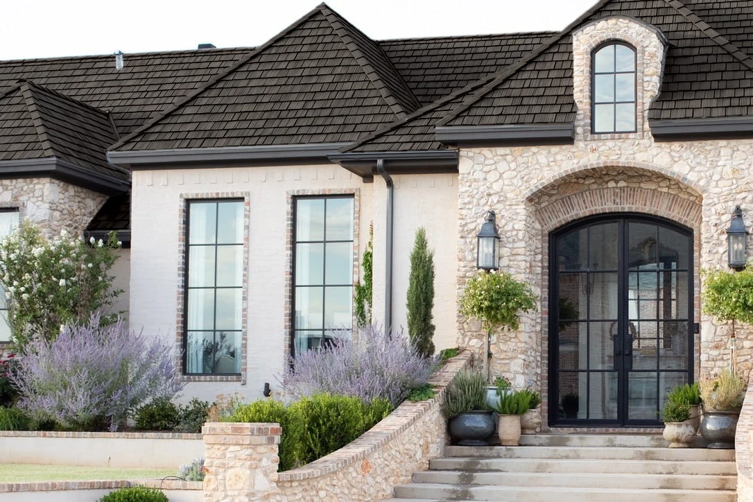 Roof comparison showing dark shake-style roofing on a stone and stucco home.