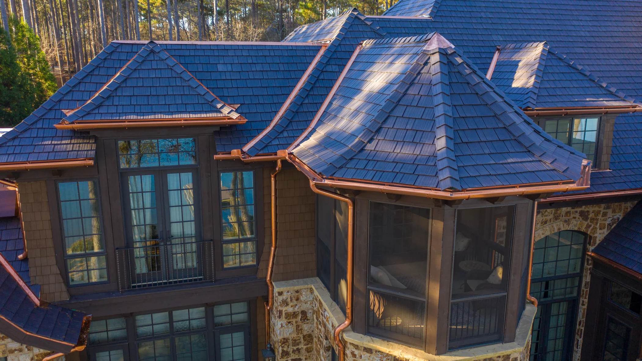 Close-up of an Enviroshake roof with curved eaves and copper trim above a screened porch.