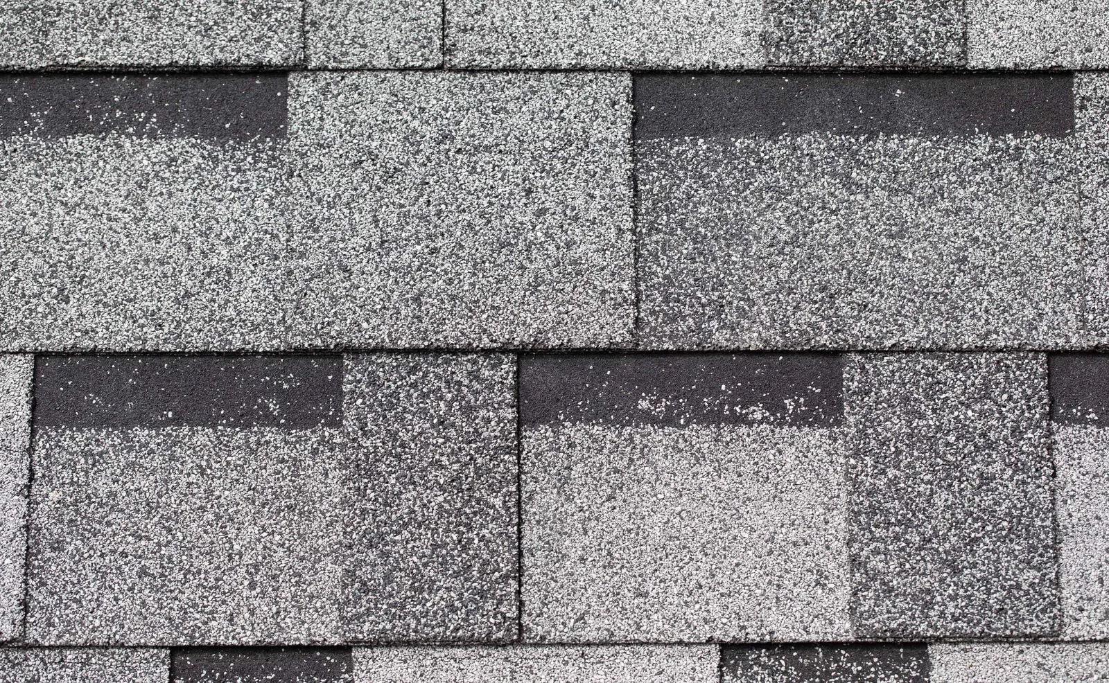 A closeup swatch of grey standard 3-tab asphalt shingles