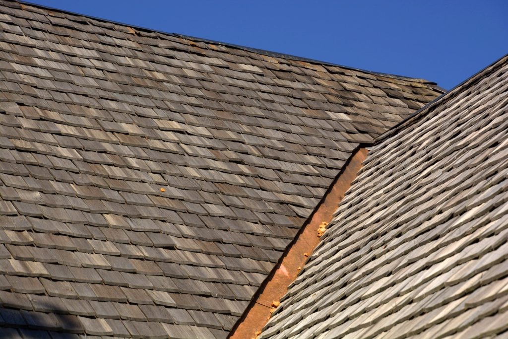 A traditional aged cedar shake roof against a cloudless blue sky
