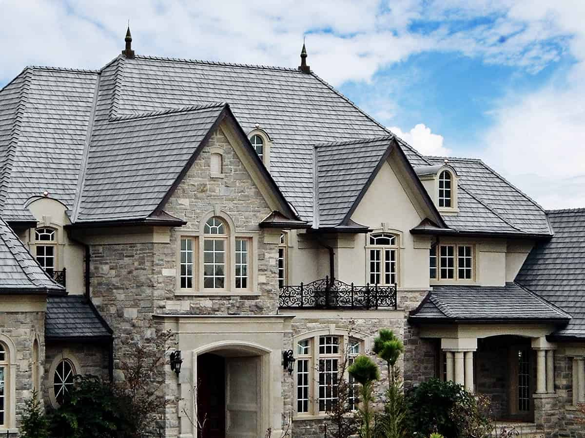 Silvered Cedar Enviroshake composite cedar shake roofing on a large stone luxury home with steep gables and multiple rooflines.