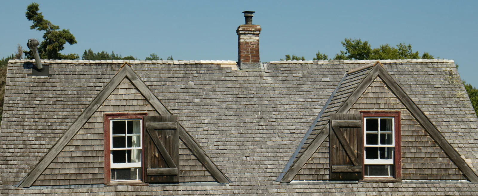 A traditional aged cedar roof with two dormers