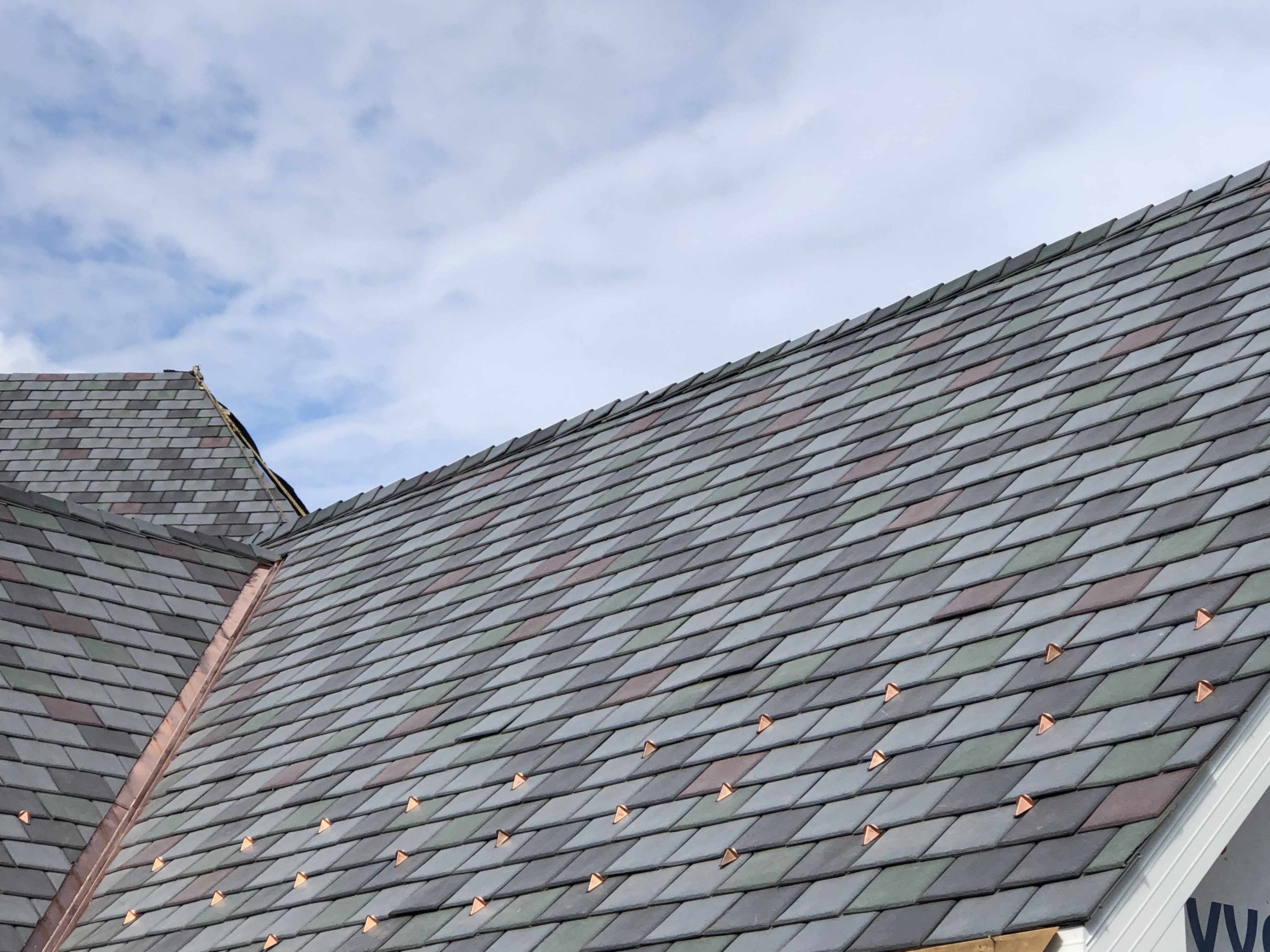 A multi-tone Enviroslate roofing system with stone grey, charcoal grey, sage green and purple tiles