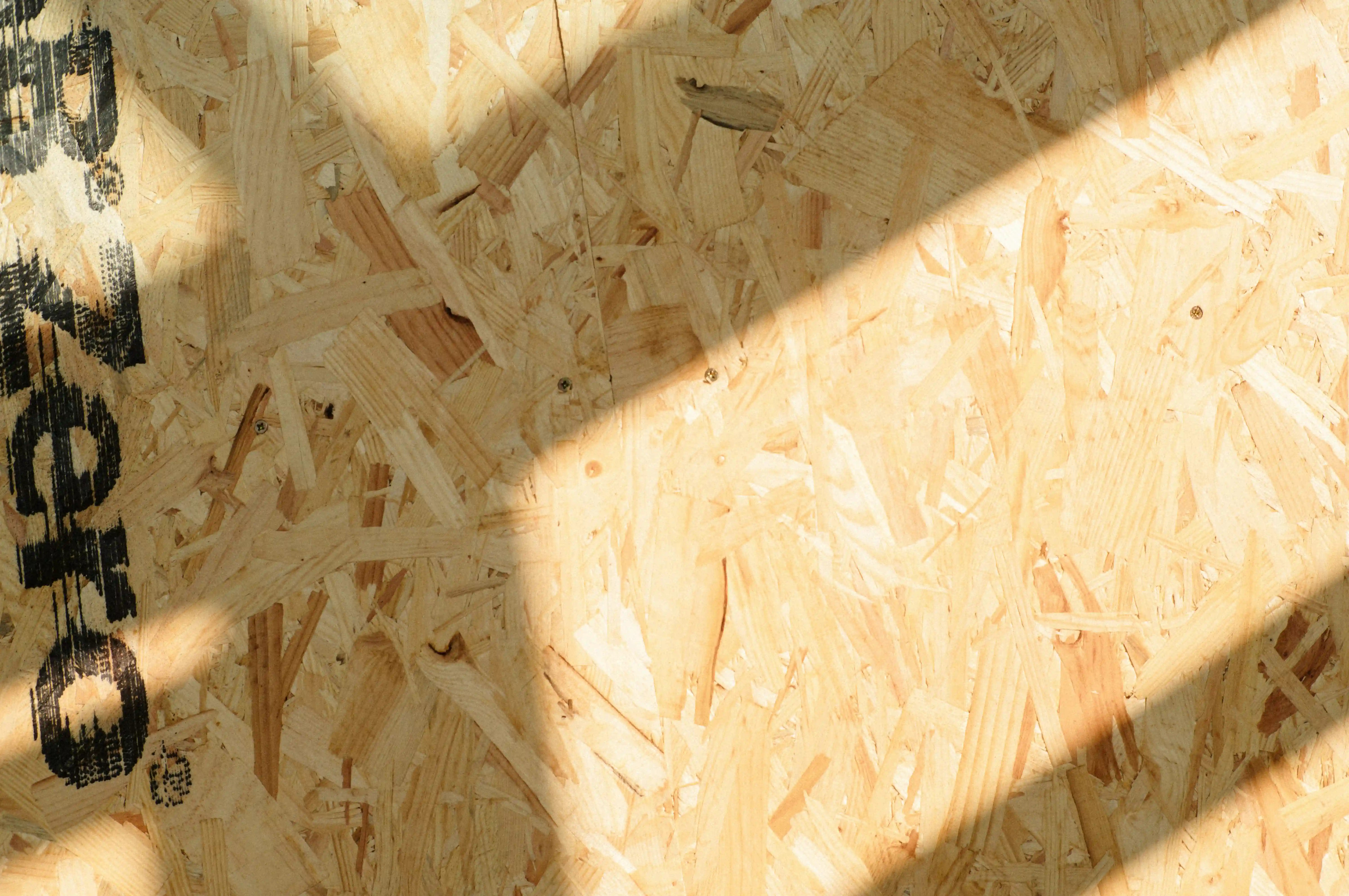 Close-up of OSB (oriented strand board) roof decking with sunlight streaming across the surface