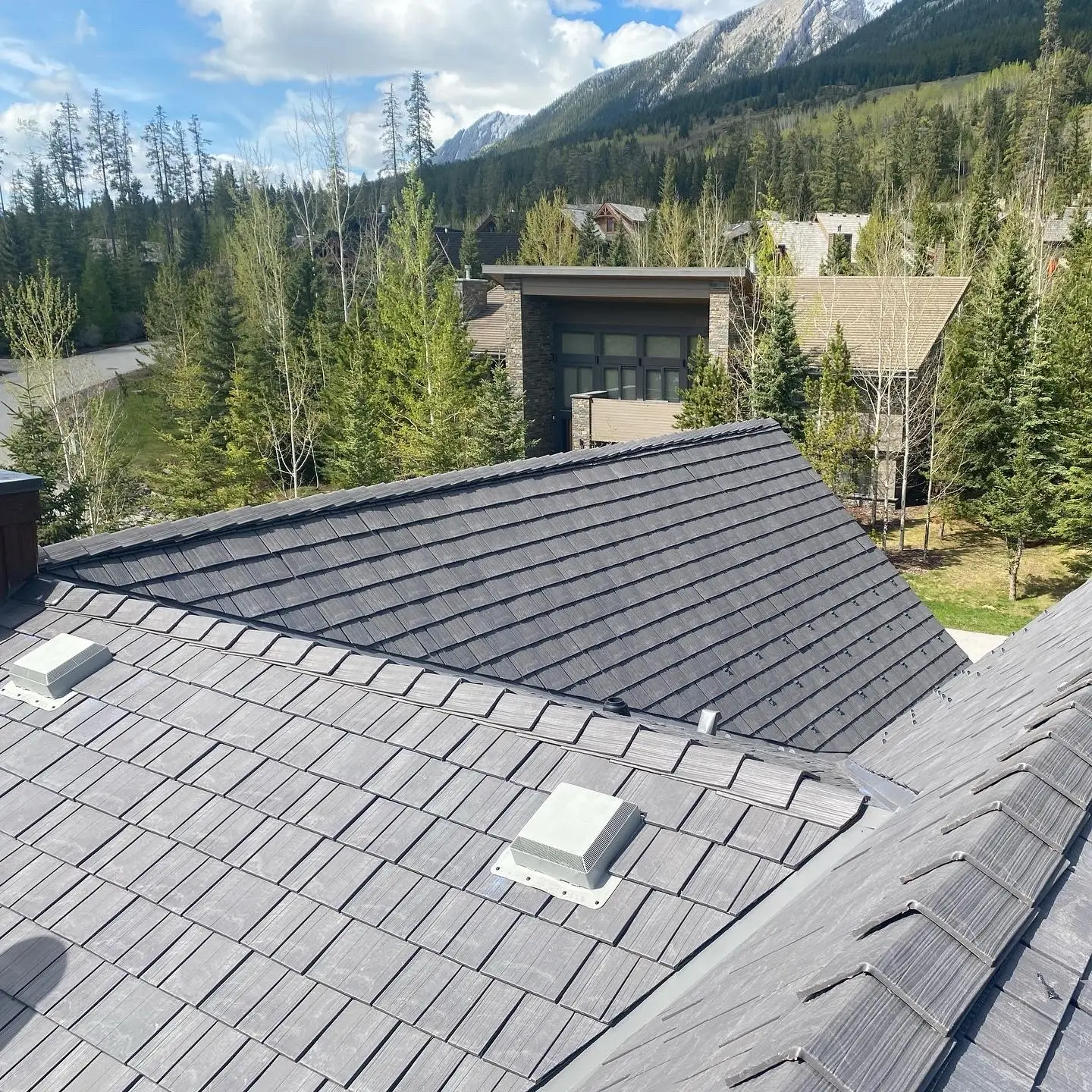 Aerial view of silvered cedar Enviroshake roof tiles installed on a large home in a forested mountain community