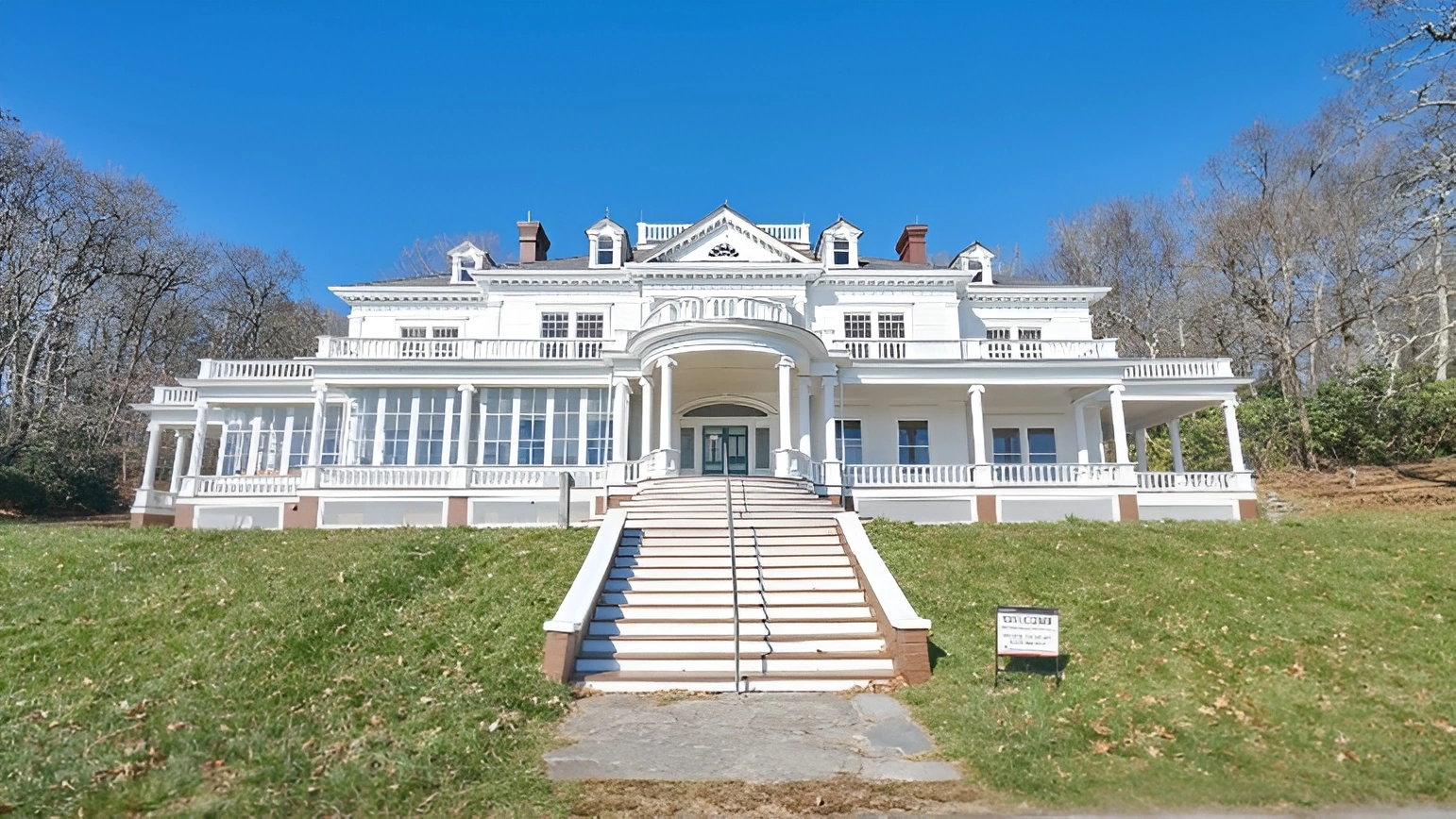 Grand white colonial-style mansion with a gray Enviroshake composite roof, columned wraparound porch, and a sweeping front staircase set on a landscaped lawn