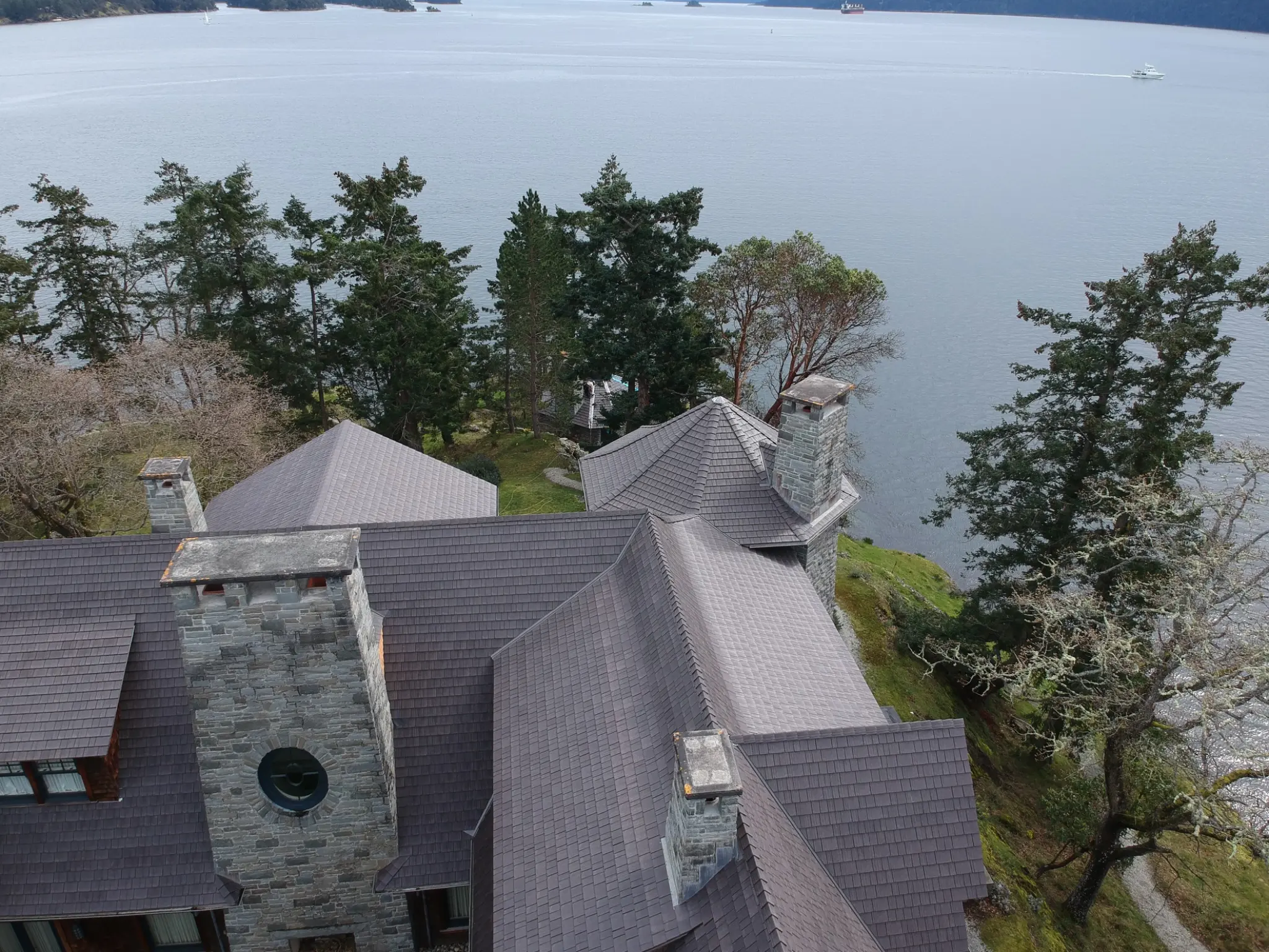 Aged Cedar Enviroshake composite cedar shake roof on a waterfront home surrounded by trees.