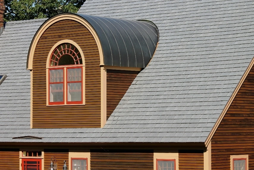Silvered Cedar Enviroshake composite cedar shake roofing on a traditional wood-sided home with a curved dormer.