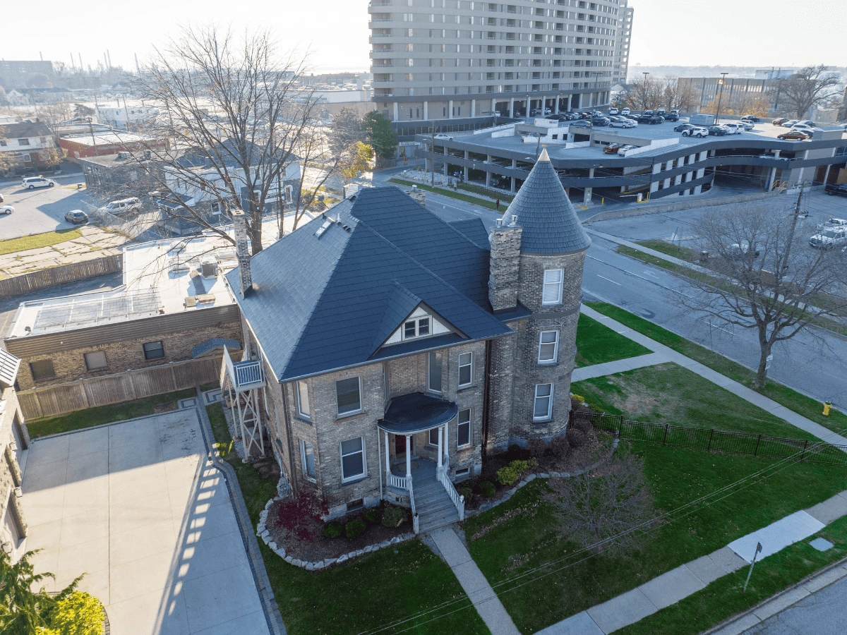 Enviroshake composite cedar shake roofing on a historic brick home with a distinctive round turret and conical roof.