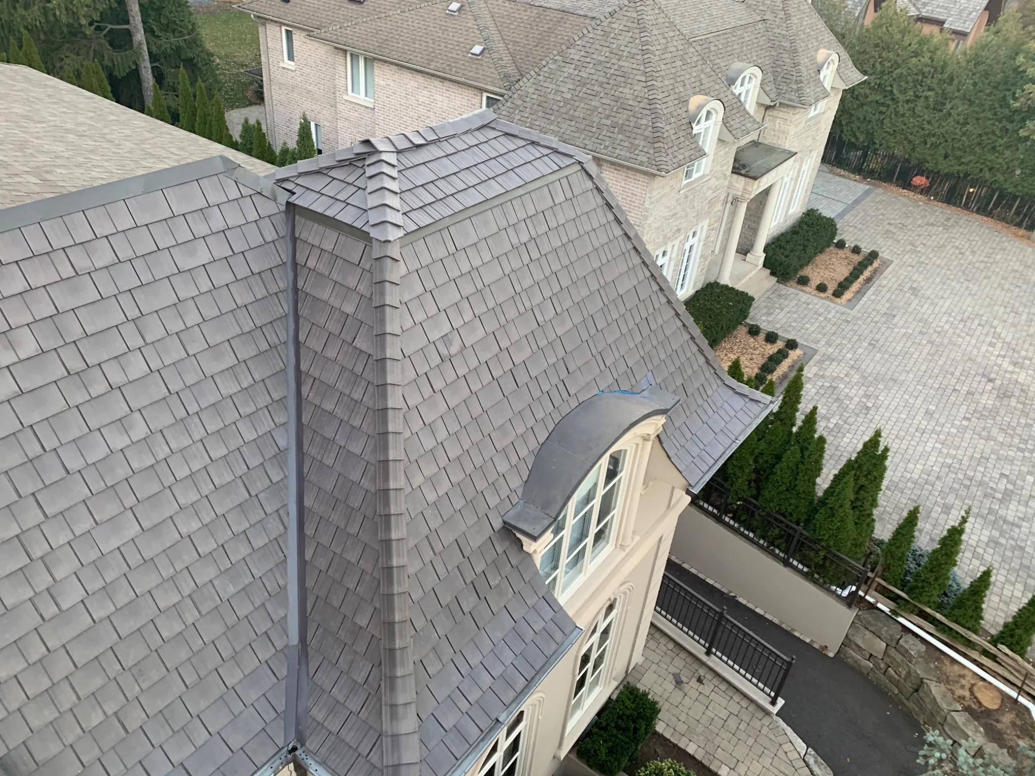 Enviroshake composite cedar shake roofing on a luxury home with steep curved rooflines and dormer windows.