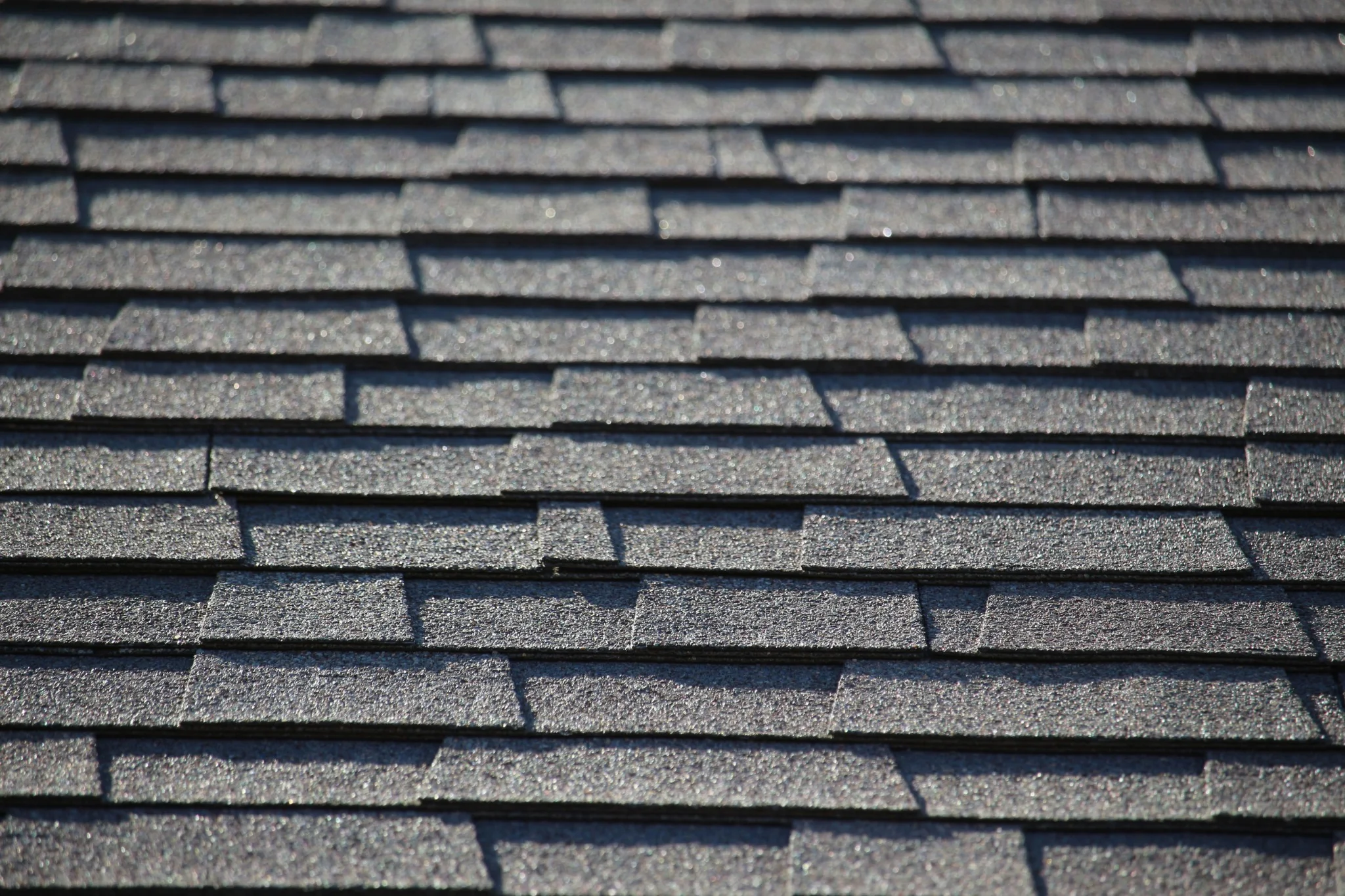 Asphalt shingle roofing close-up showing the layered texture and staggered pattern of architectural shingles.
