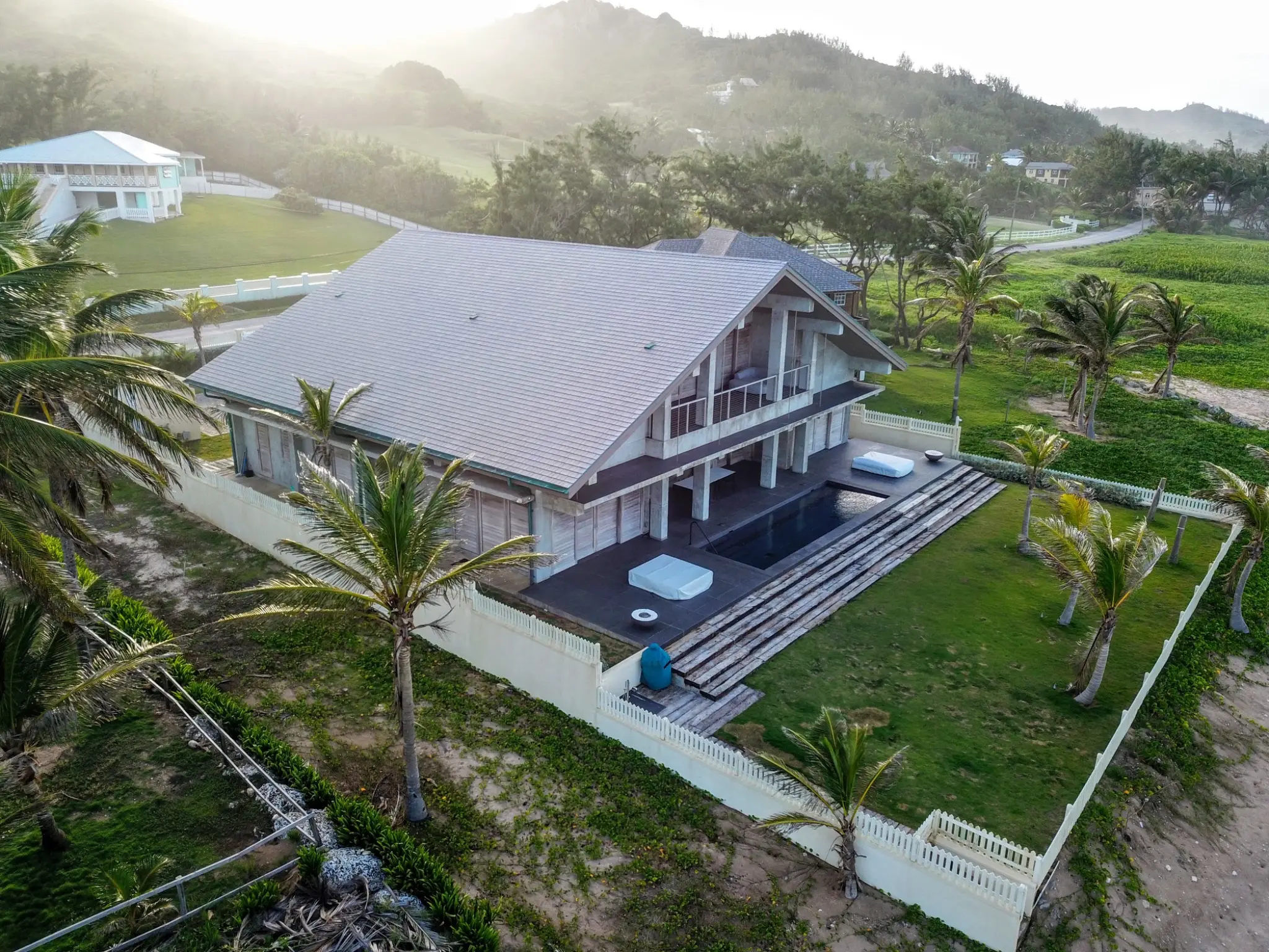 Enviroshake composite cedar shake roofing on a luxury tropical home surrounded by palm trees and lush landscaping.