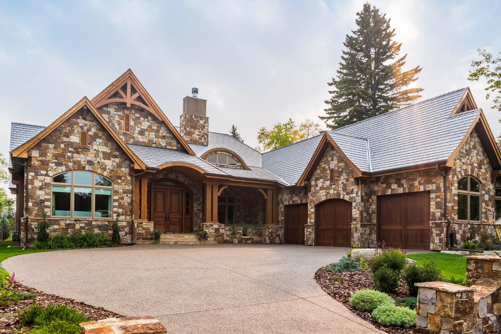 Silvered Cedar Enviroshake composite cedar shake roofing on a luxury stone home with steep gables and natural wood accents.