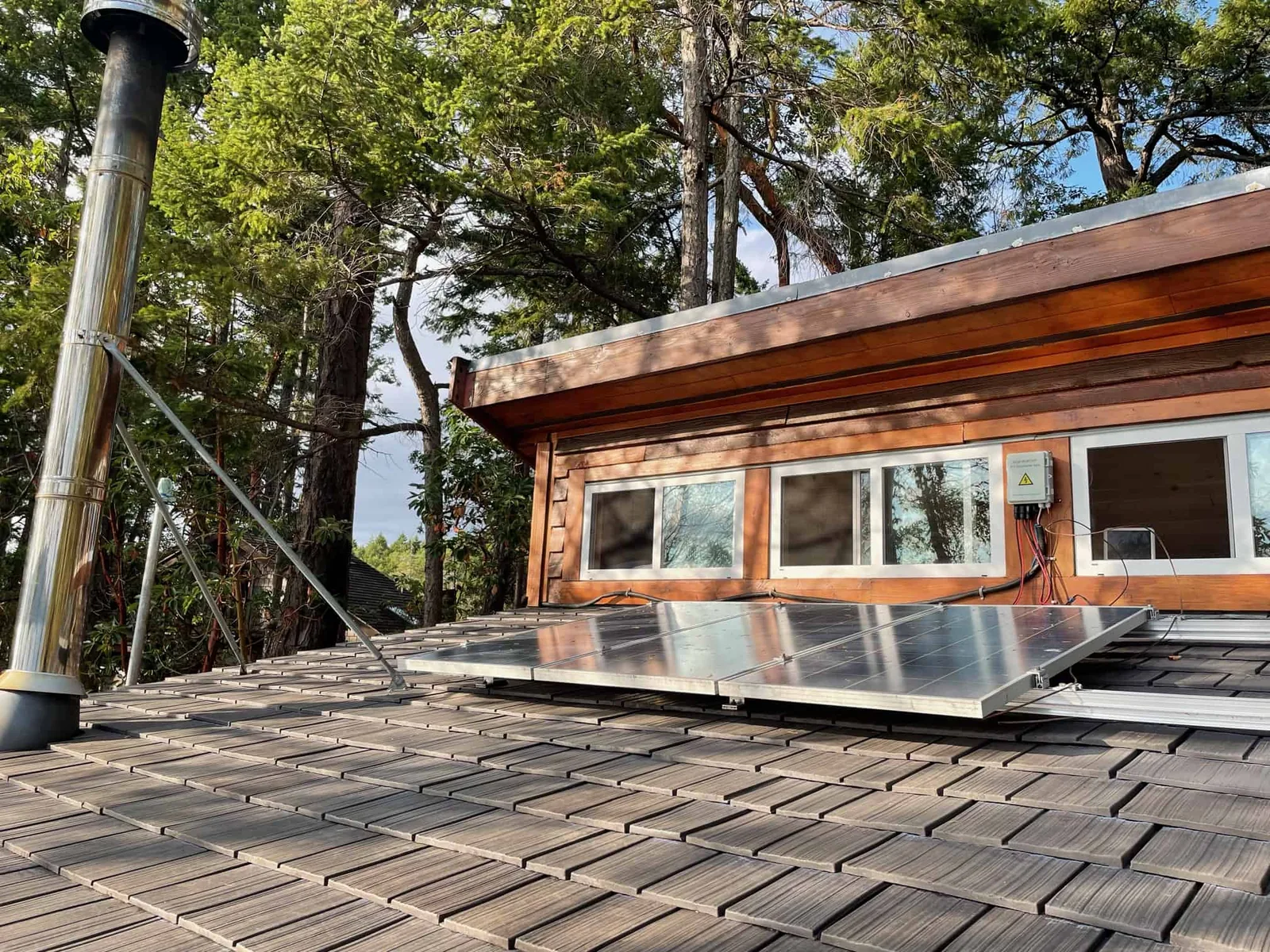 Solar panels installed on an Enviroshake composite cedar shake roof surrounded by mature trees.