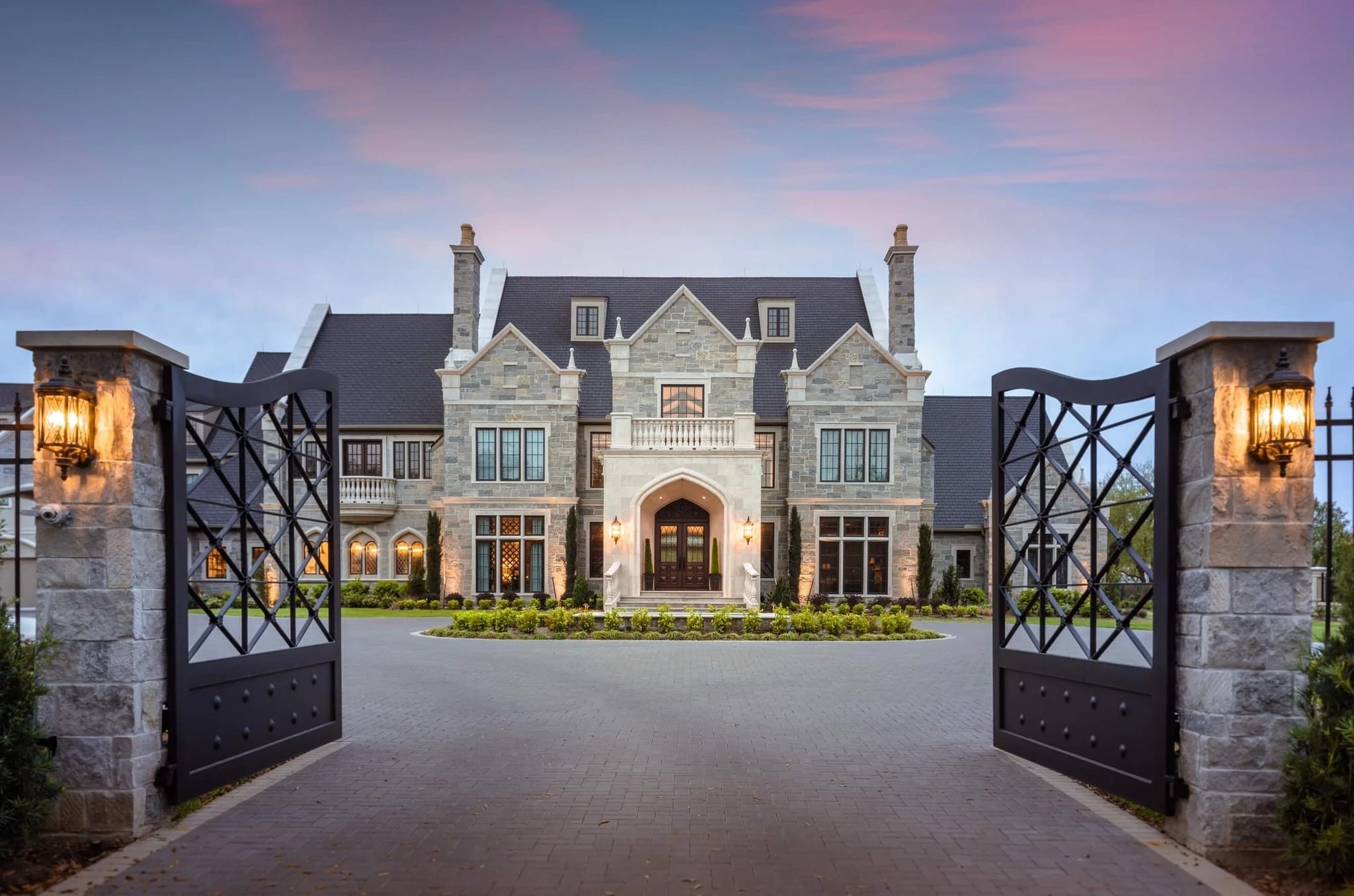 Luxury stone estate featuring Enviroslate composite slate roofing at sunset.
