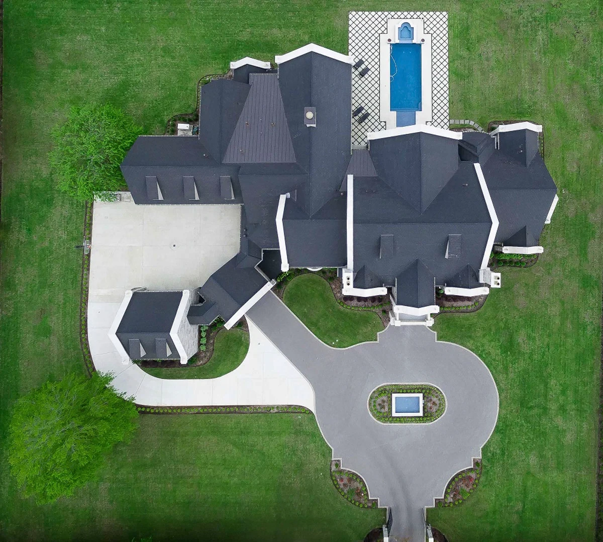 Aerial view of stone estate with Enviroslate composite slate roofing overlooking a landscaped courtyard and swimming pool.