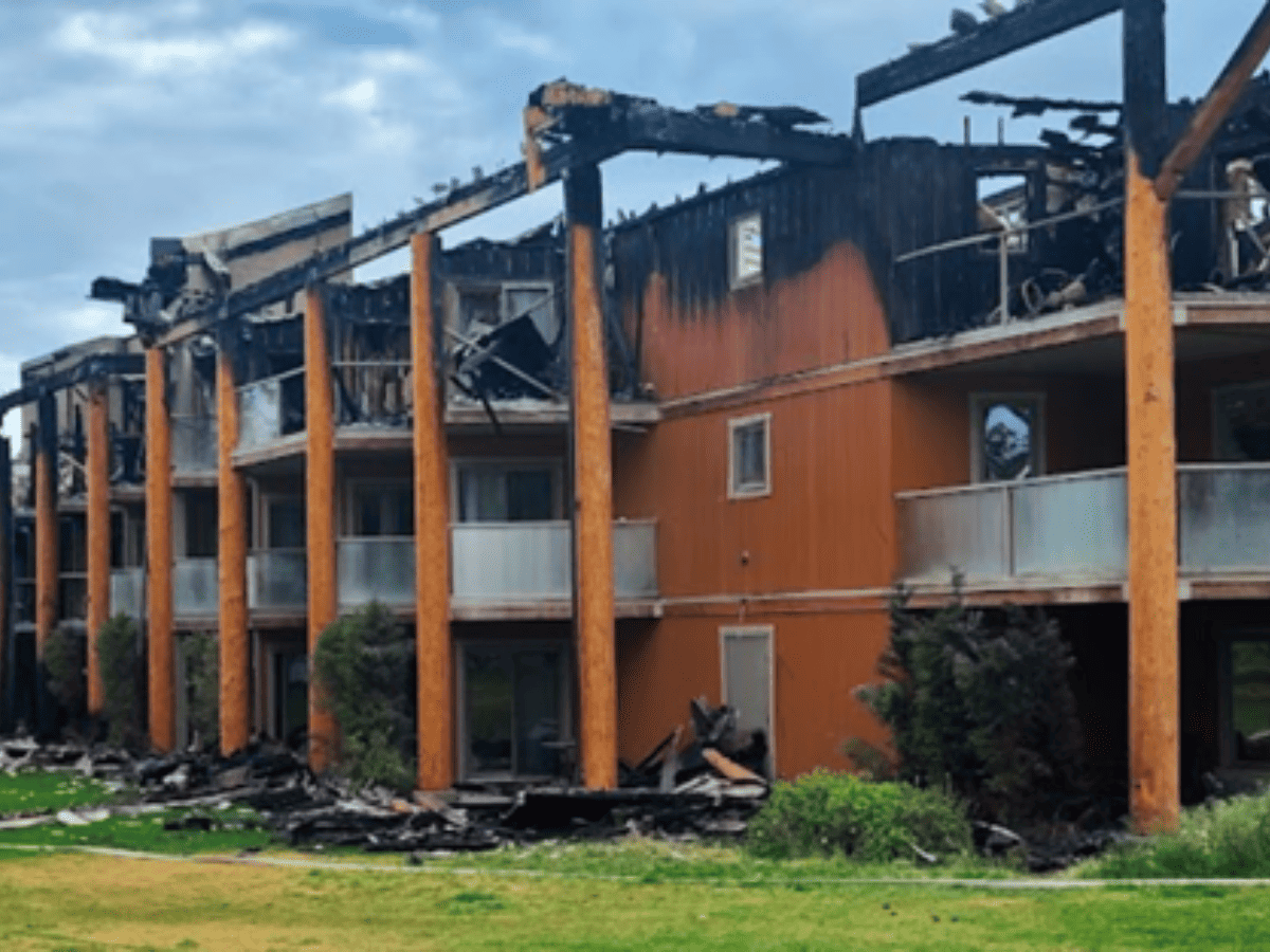 Fire-damaged mountain lodge with severe roof and upper-level structural damage following a major fire.