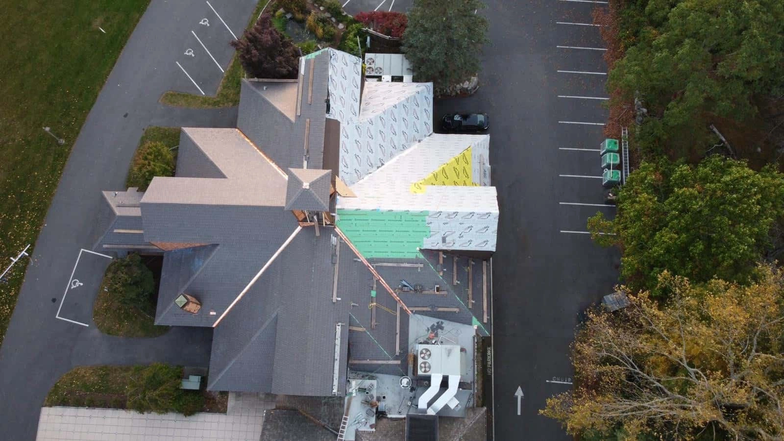 Aerial view of an Enviroshake composite cedar roof installation in progress on a large commercial building with multiple intersecting rooflines.