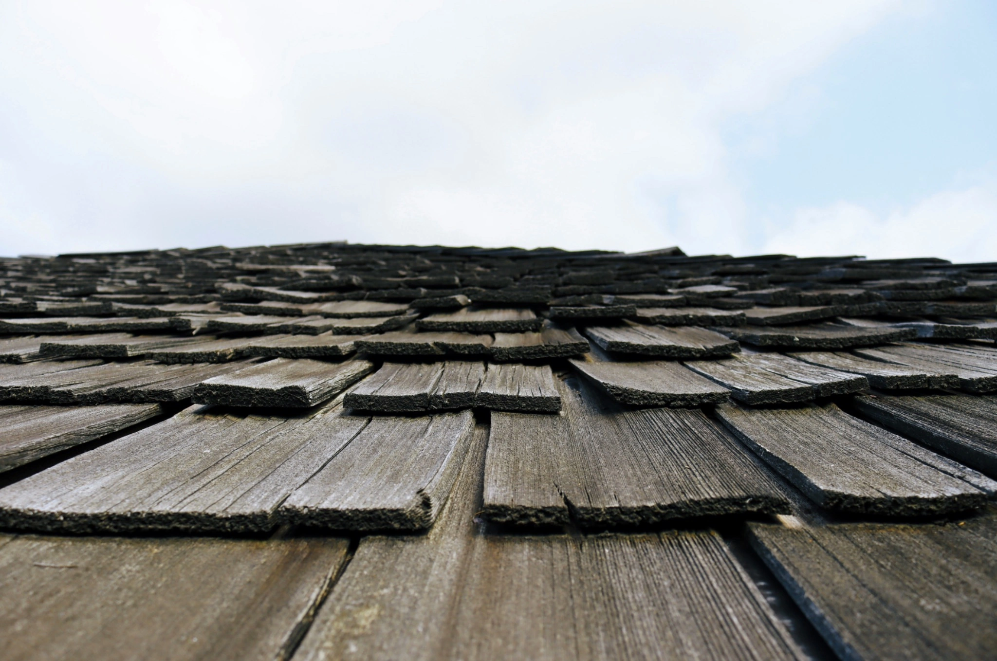 Low-angle view across a worn natural cedar shake roof