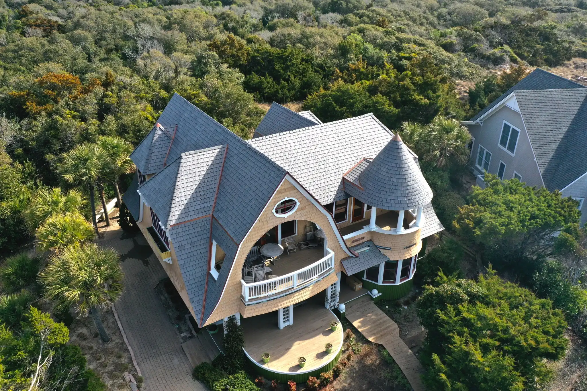 Aerial view of a coastal home featuring Enviroshake composite cedar shake roofing with distinctive curved rooflines and a turret.