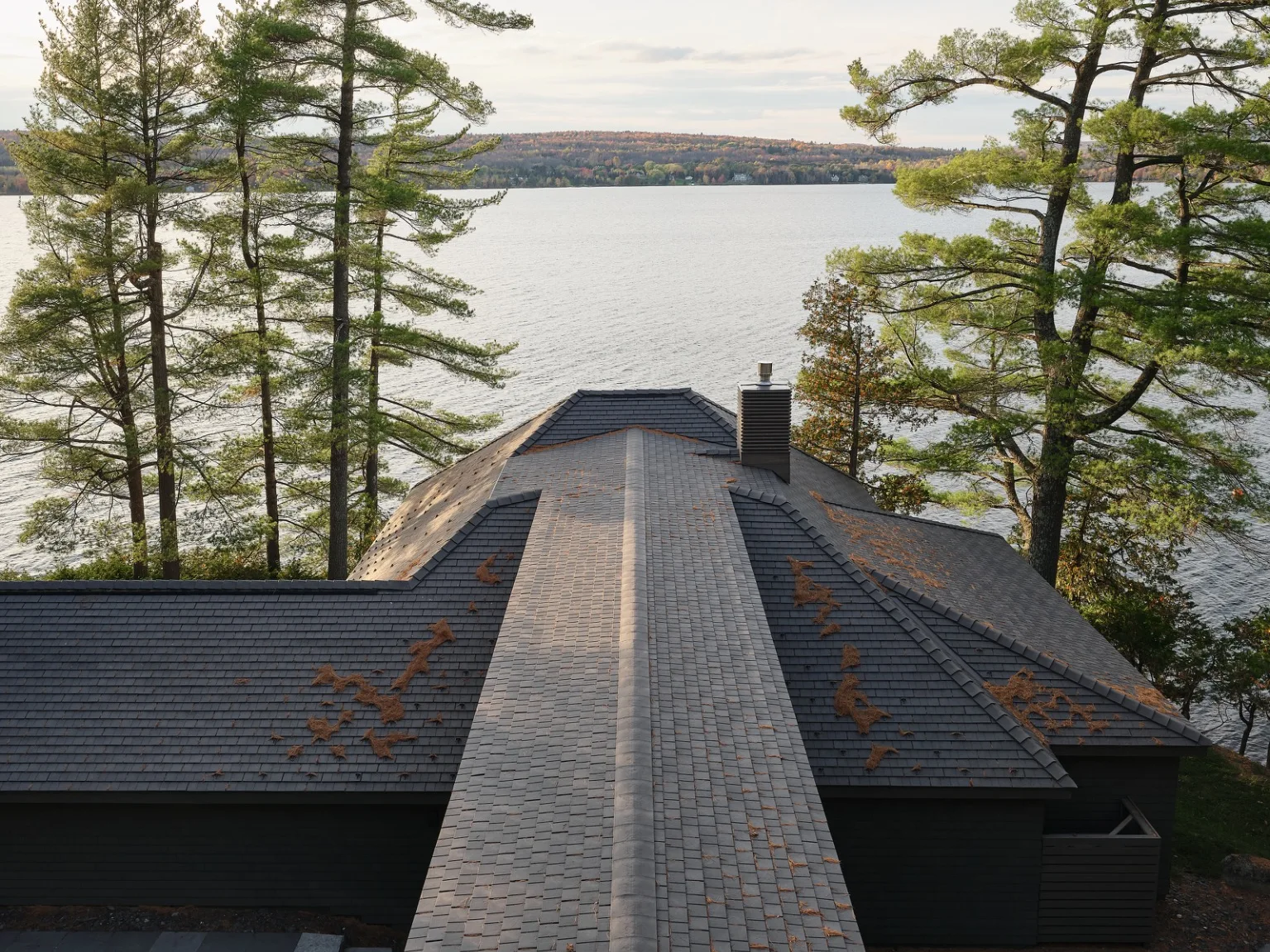 Aged Cedar Enviroshingle composite roofing on a lakeside home surrounded by mature pine trees.