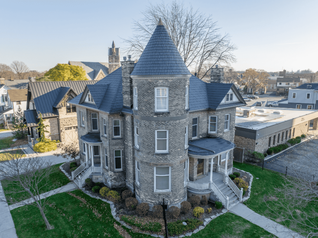 Aged Cedar Enviroshake composite cedar shake roofing on a historic stone home with a prominent turret.