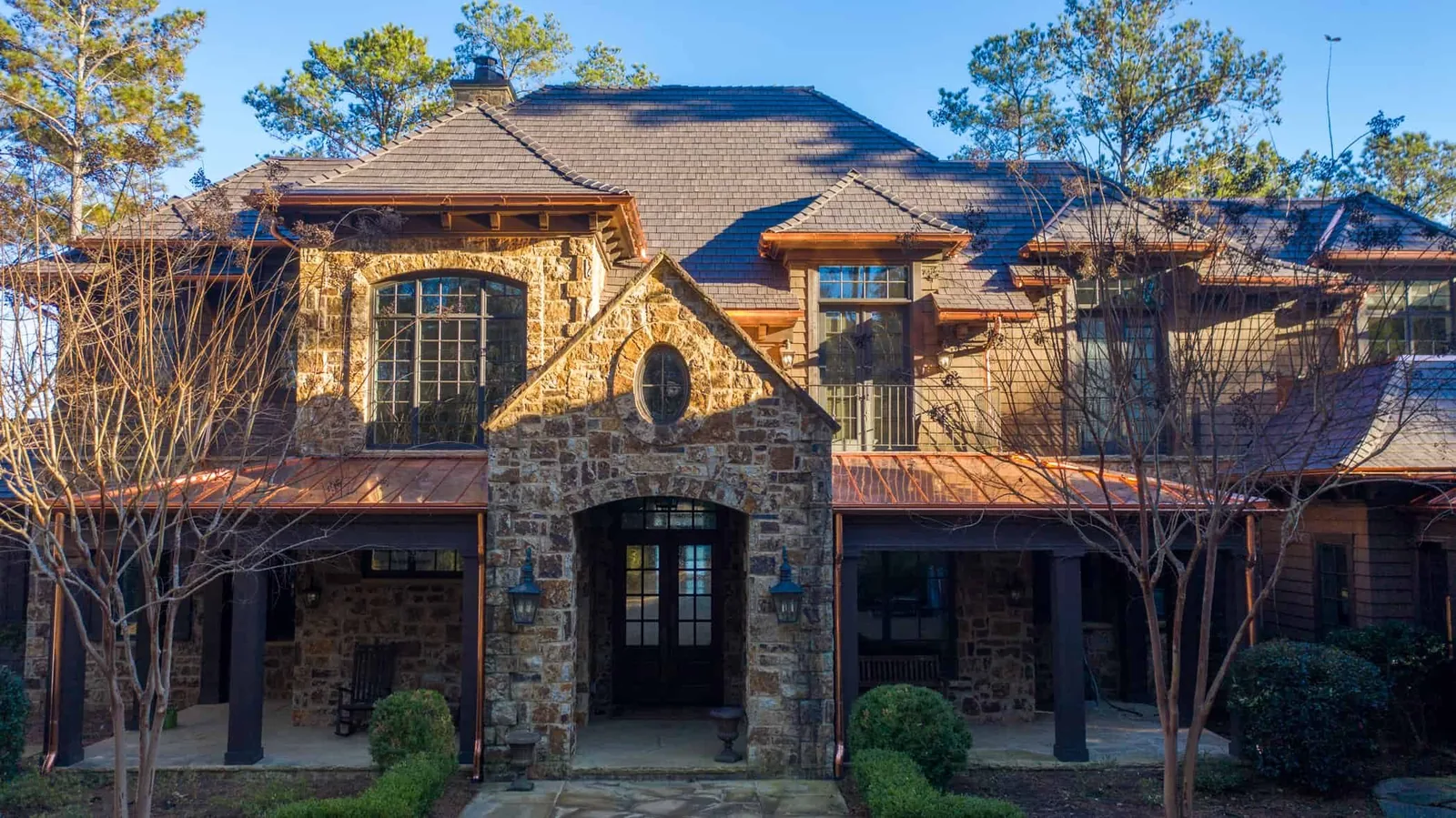 Enviroshake composite cedar shake roofing on a luxury stone home with copper accents and detailed rooflines.