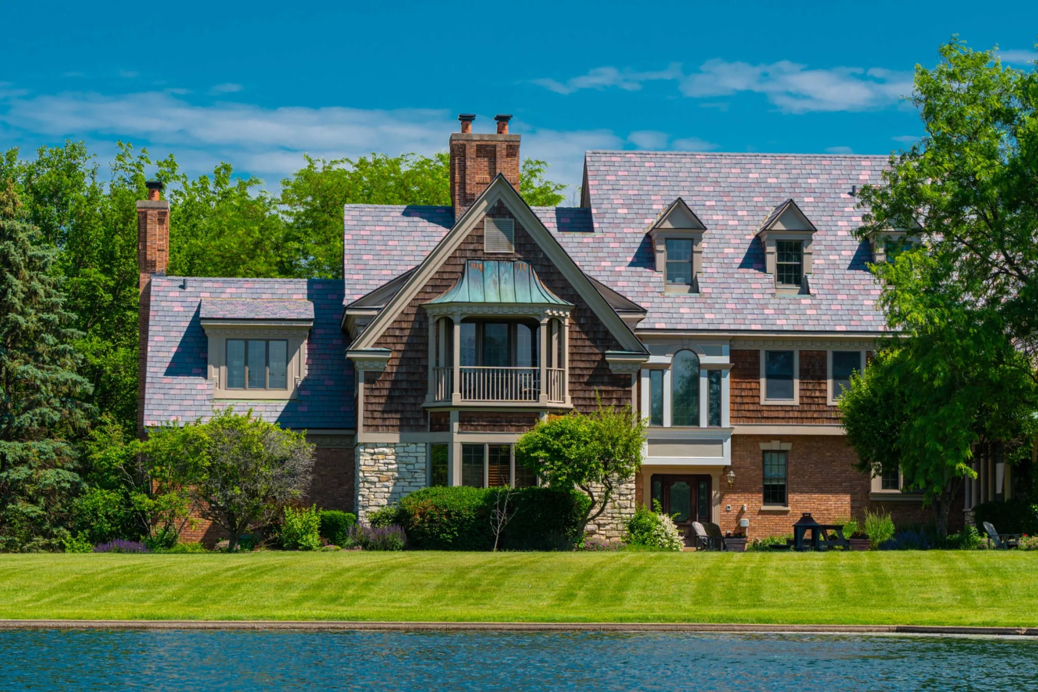 Tudor-style brick home with an Enviroslate Multi-Tone roof beside a lake