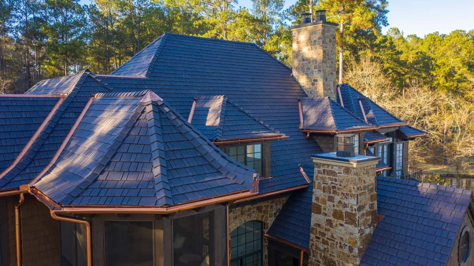 Enviroshake composite cedar shake roofing on a luxury stone home with copper accents and detailed rooflines.