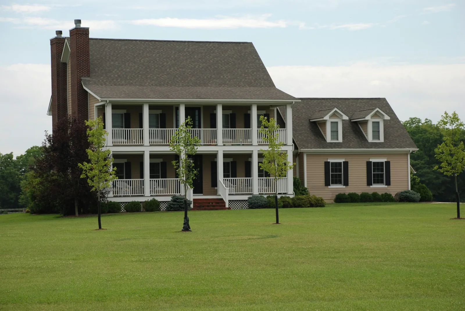White colonial home with a dark asphalt shingle roof and front porch