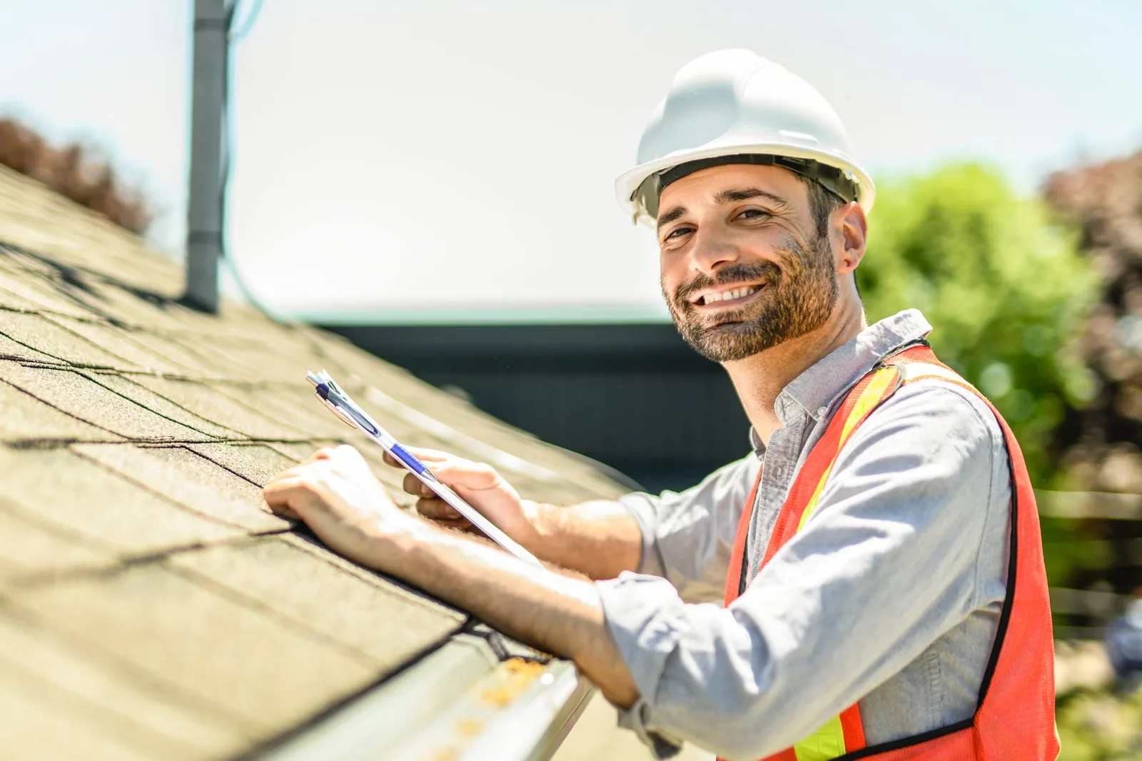 Roofing inspector in a hard hat documenting shingle condition