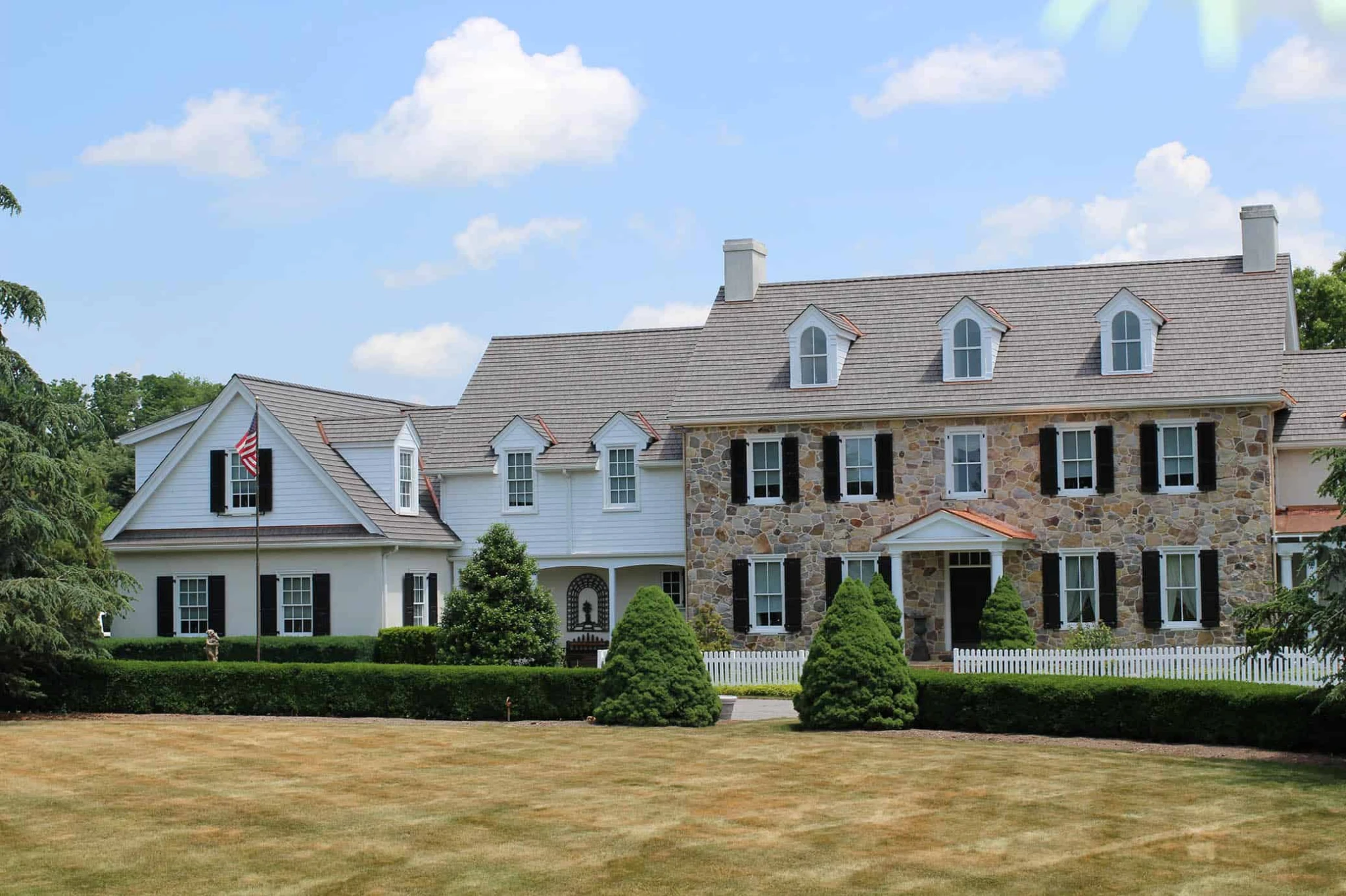 Stone colonial home with an Enviroshake roof and manicured lawn