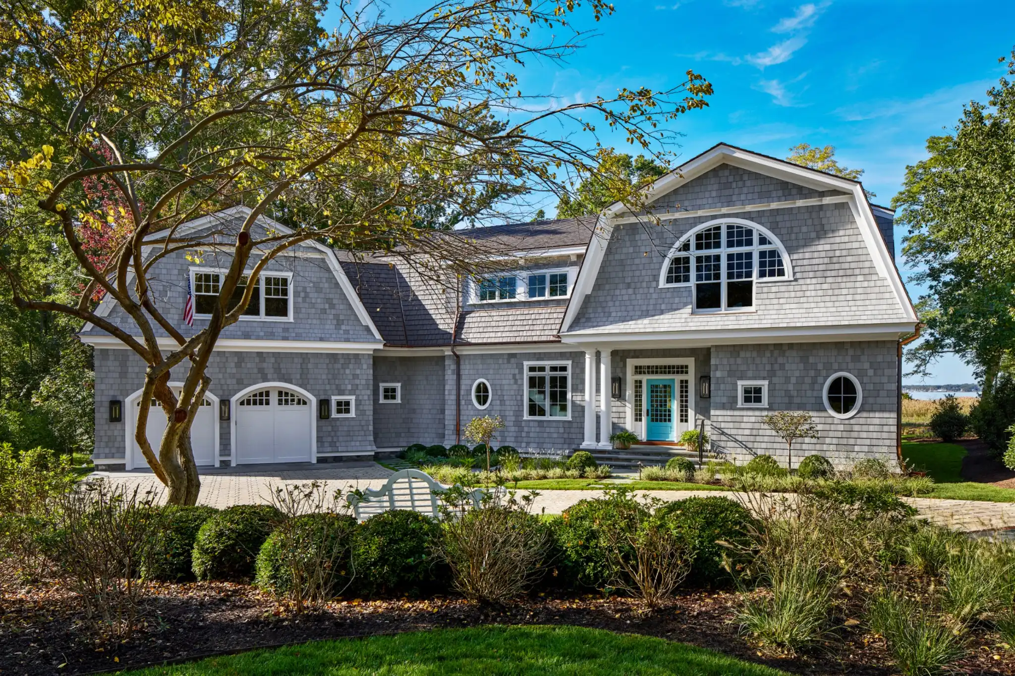 Shingle-style home with a gambrel roof and landscaped front yard