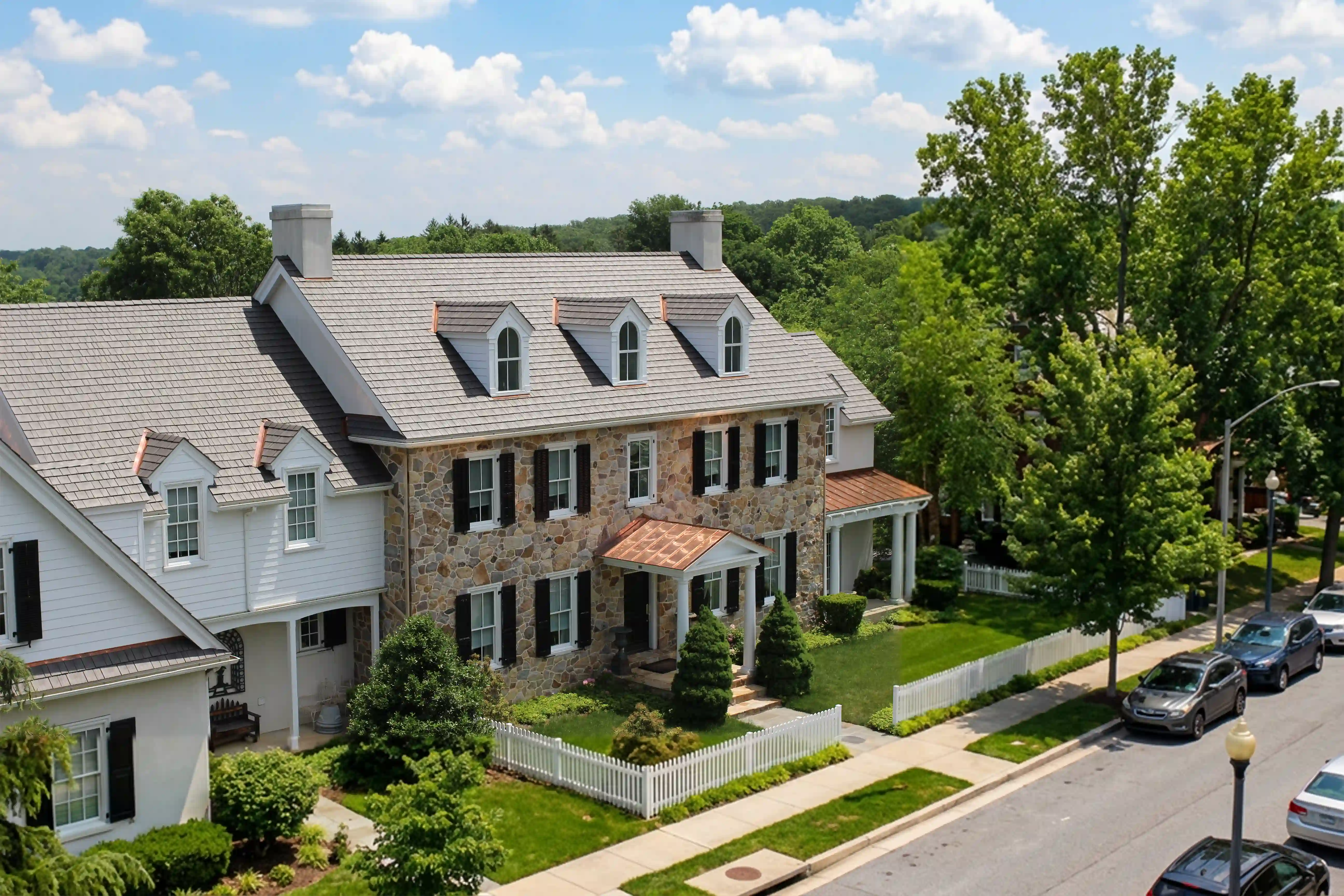 Aerial view of a colonial-style stone home with an Aged Cedar Enviroshake roof