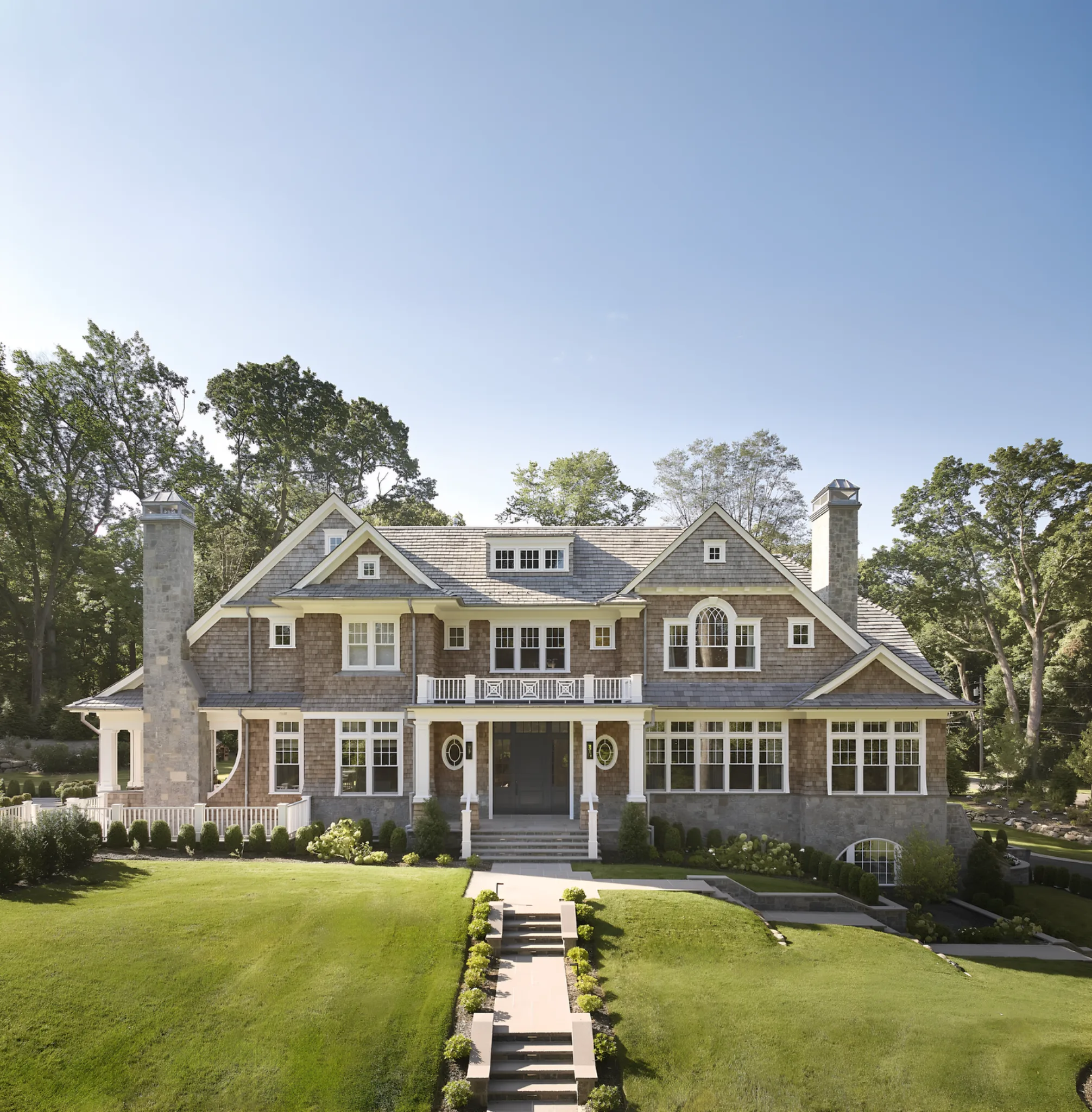 Shingle-style home with an Enviroshake roof and front steps through a sloped lawn
