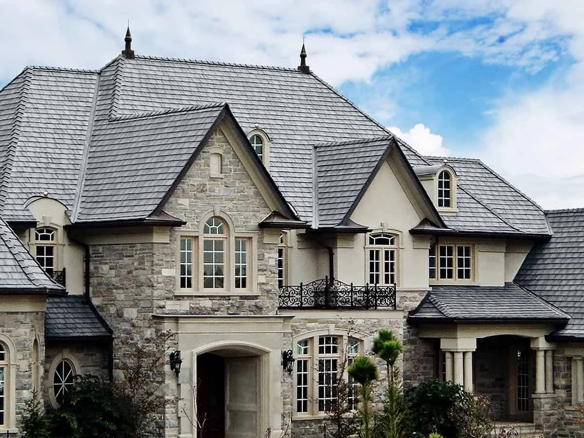 Silvered Cedar Enviroshake composite cedar shake roofing on a large stone luxury home with steep gables and multiple rooflines.