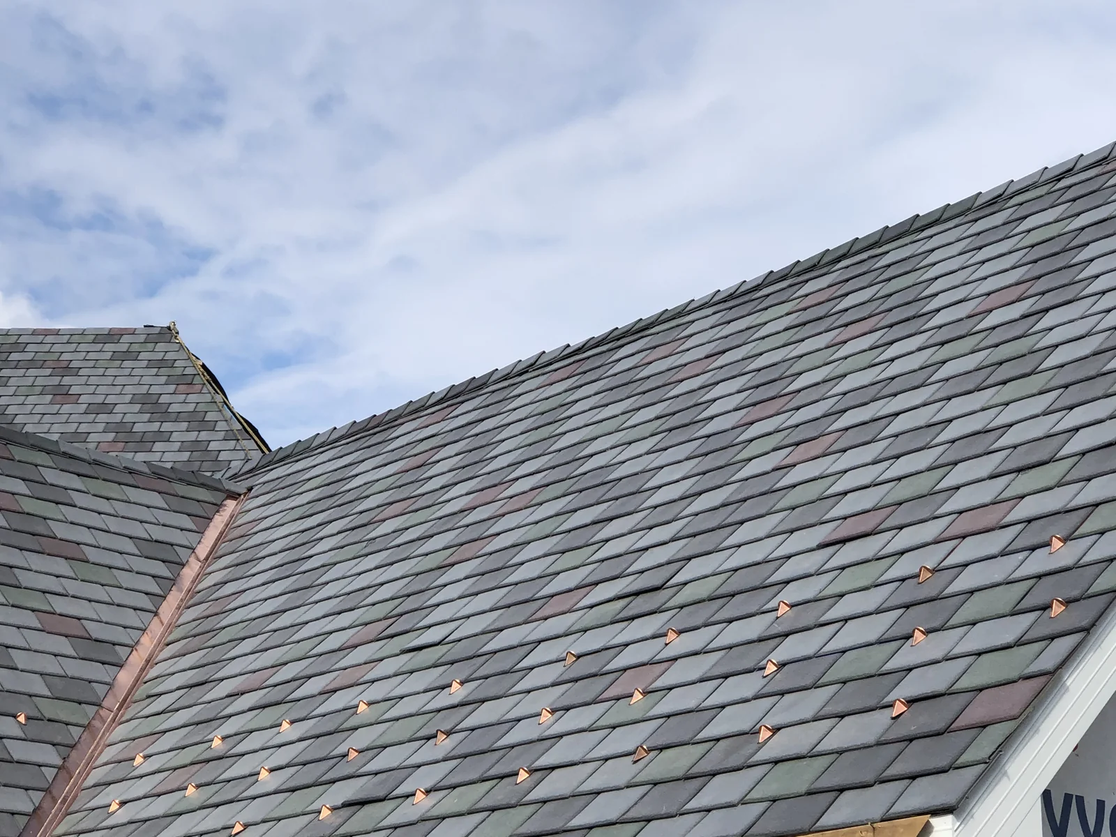 A multi-tone Enviroslate roofing system with stone grey, charcoal grey, sage green and purple tiles
