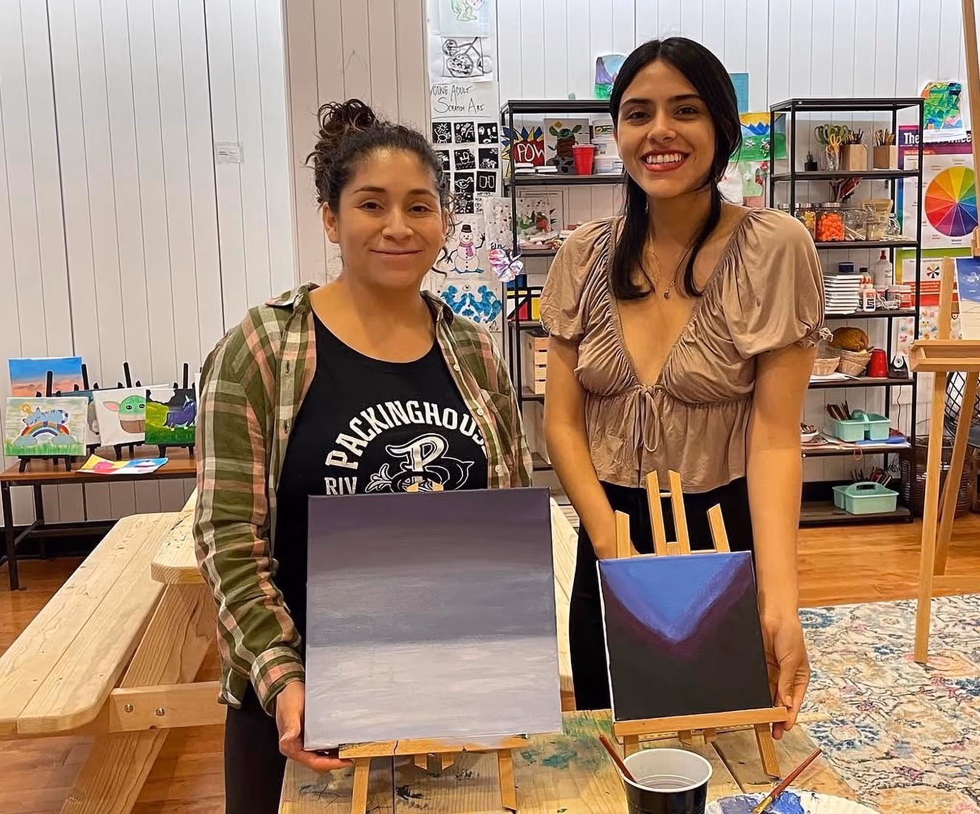 Two Artists Holding Completed Projects