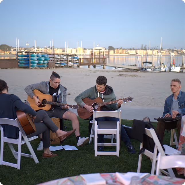 A group of people sitting around each other playing guitars.