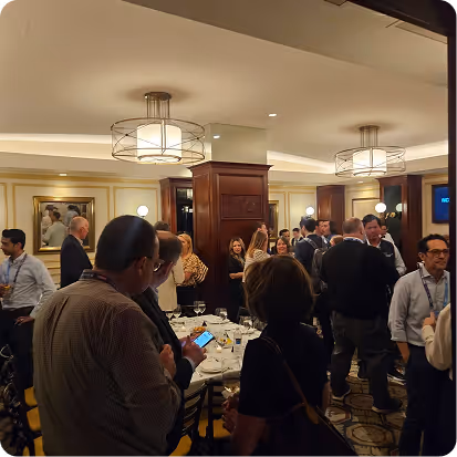Group of people socializing in a warmly lit room with wooden panels and art on walls.