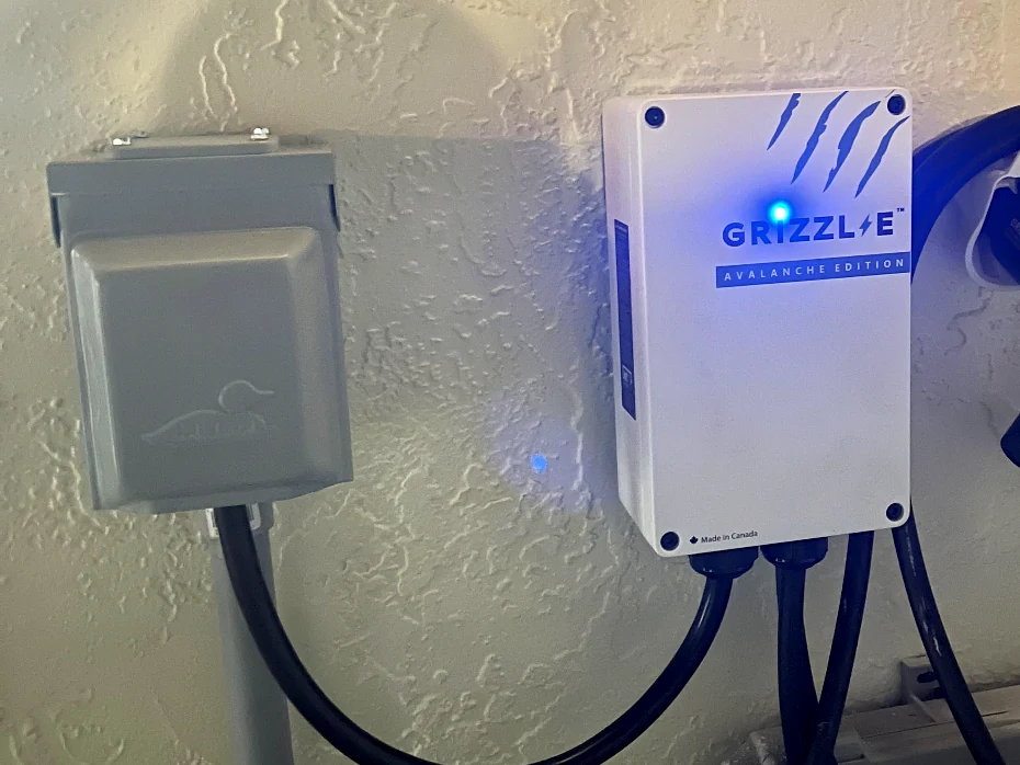 Grizzl-E EV charger mounted next to an outdoor disconnect switch, with wiring run in conduit