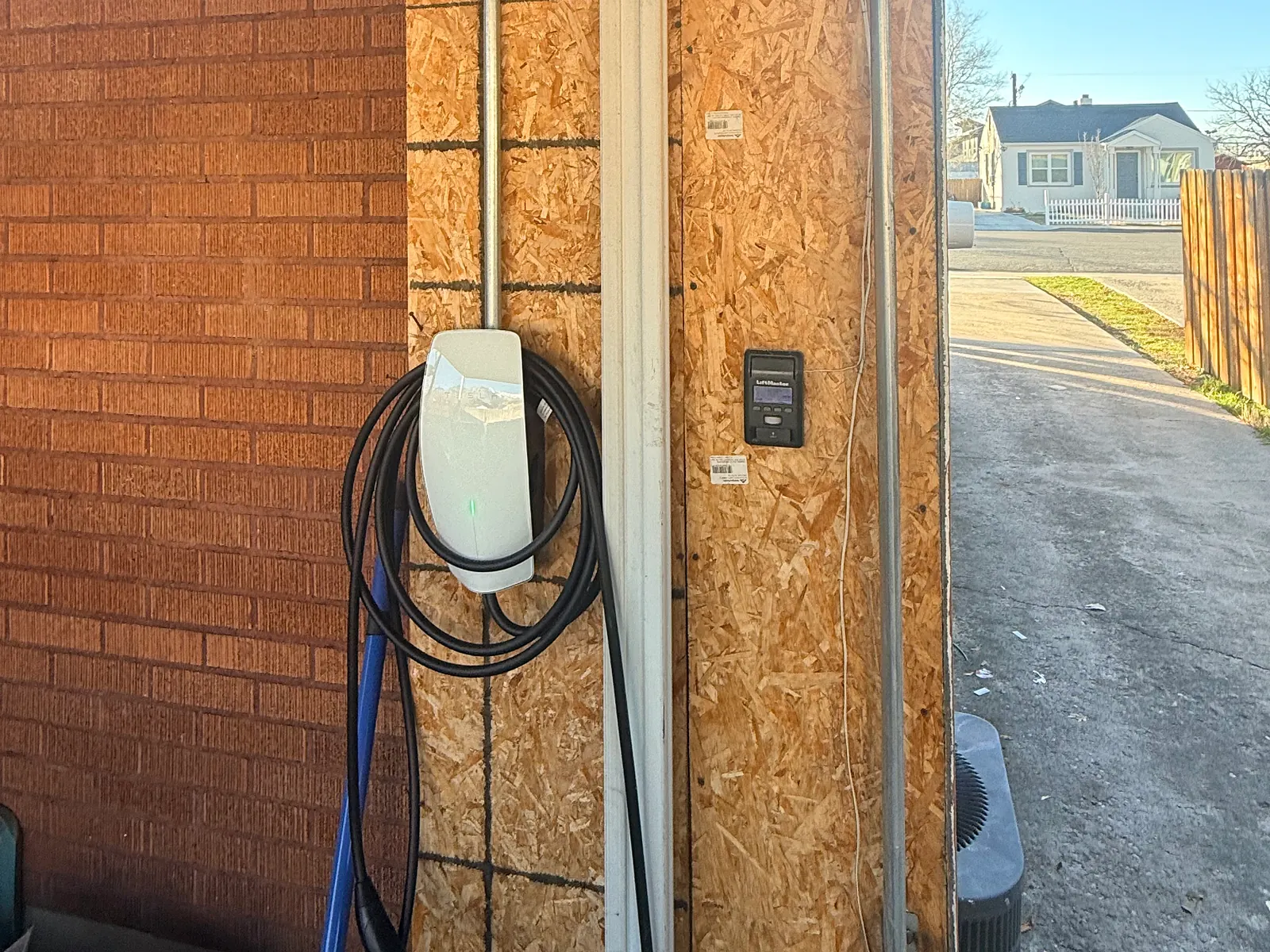 Tesla Wall Connector installed inside a garage door opening with conduit run down the wall