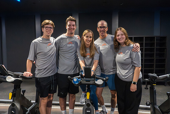 Five family members in matching shirts posing in a spin studio