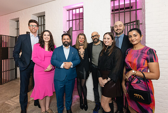 Group of well dressed people smiling with old fashion prison doors behind them