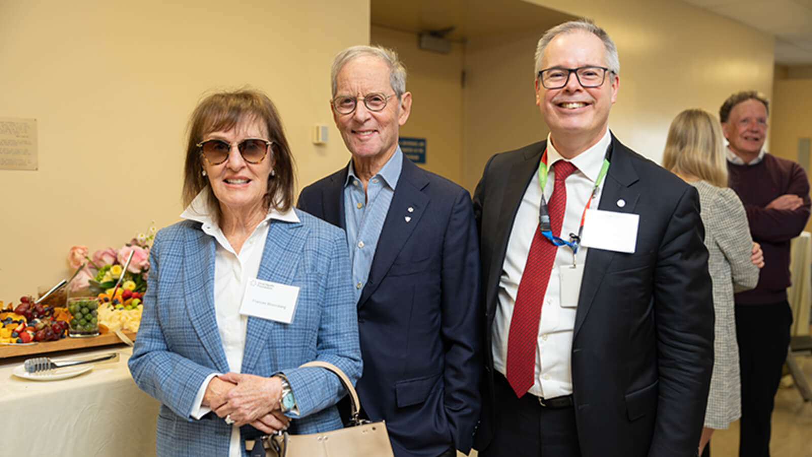 Three well dressed people smiling at an event