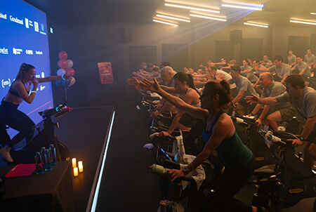 Spin class with instructor in front of class on a stage